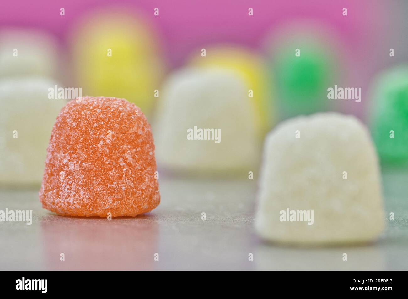 Gummi Tropft zuckerbeschichtete Süßigkeiten, Makro mit seitlichem Blickwinkel auf einem Tisch mit selektivem Fokus. Beliebte traditionelle Süßigkeiten auf Gelatinebasis, die weltweit hergestellt werden. Stockfoto