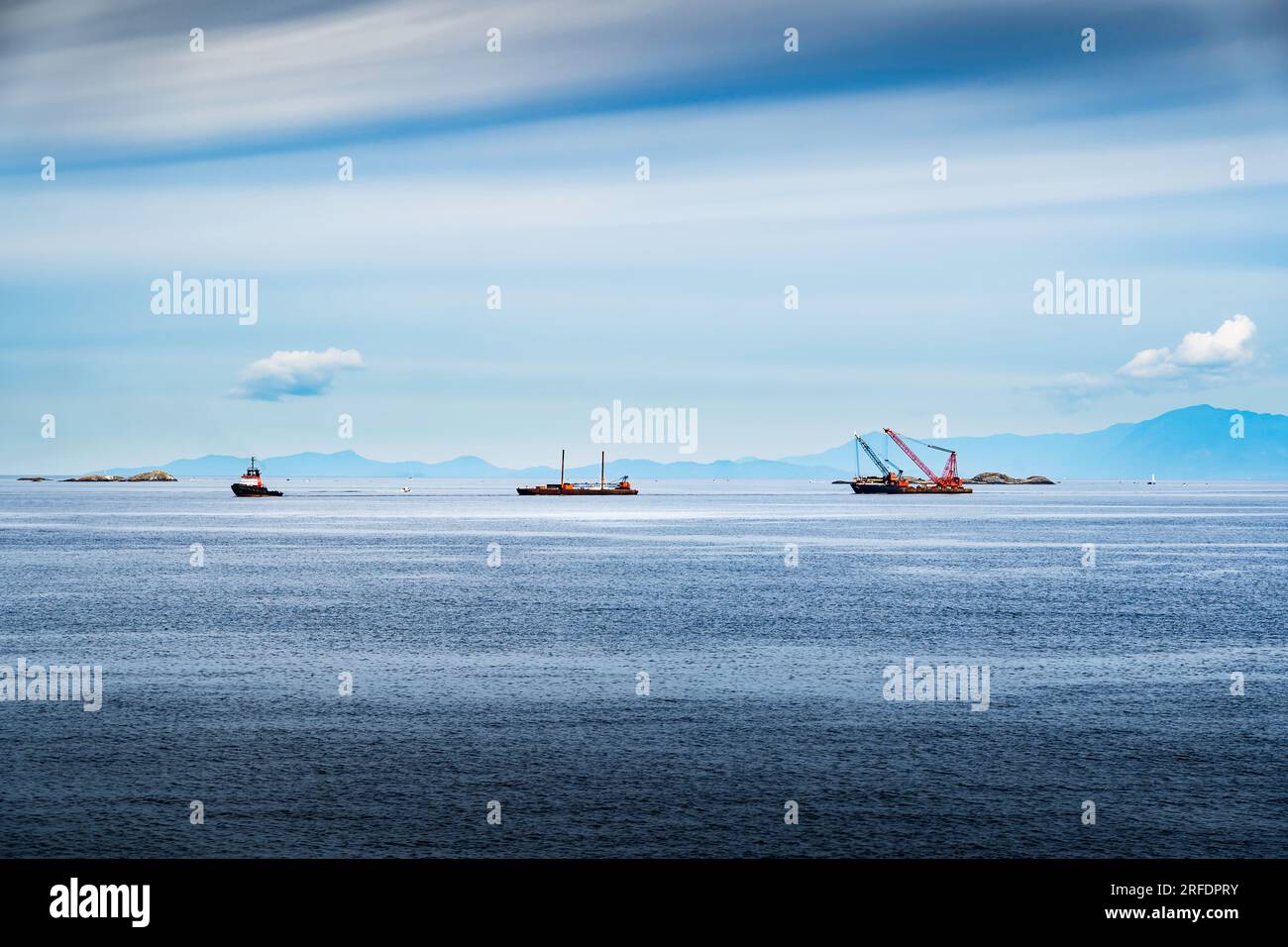 Ein Schleppboot, das Fahrausrüstung auf Lastkähnen zieht, während es durch die Gulf Islands und die Straße von Georgia in der Nähe von Nanaimo British Columbia Canada fährt. Stockfoto