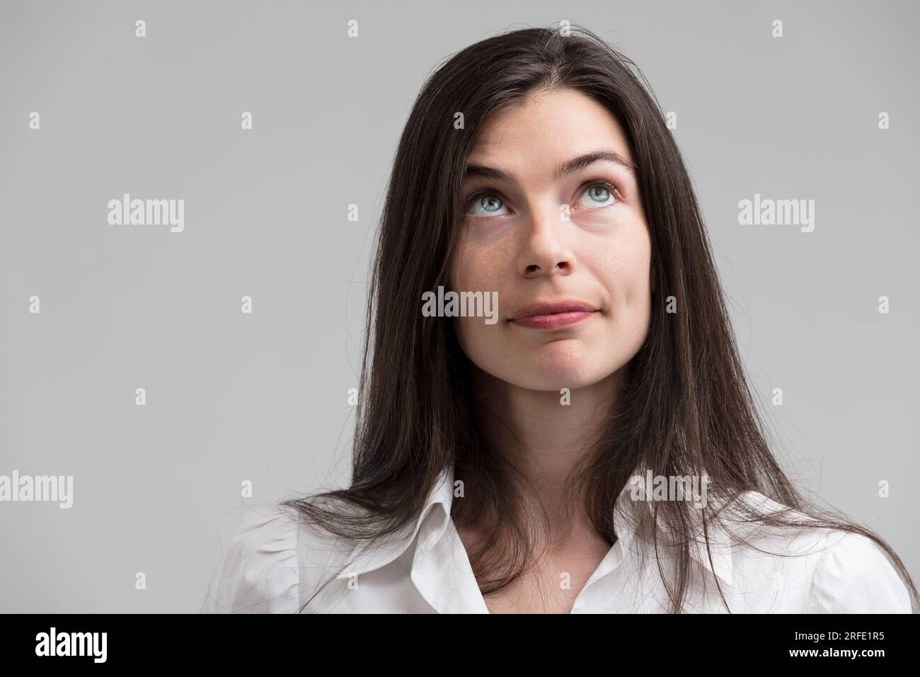 Hübsche schlanke Frau mit langen Haaren und schöner Haut sieht in Gedanken auf. Sie stellt sich vor und plant, träumt und strategisch ist, hat einen „eureka“-Moment oder p Stockfoto Hübsche schlanke Frau mit langen Haaren und schöner Haut sieht in Gedanken auf. Sie stellt sich vor und plant, träumt und strategisch ist, hat einen „eureka“-Moment oder p Stockfoto