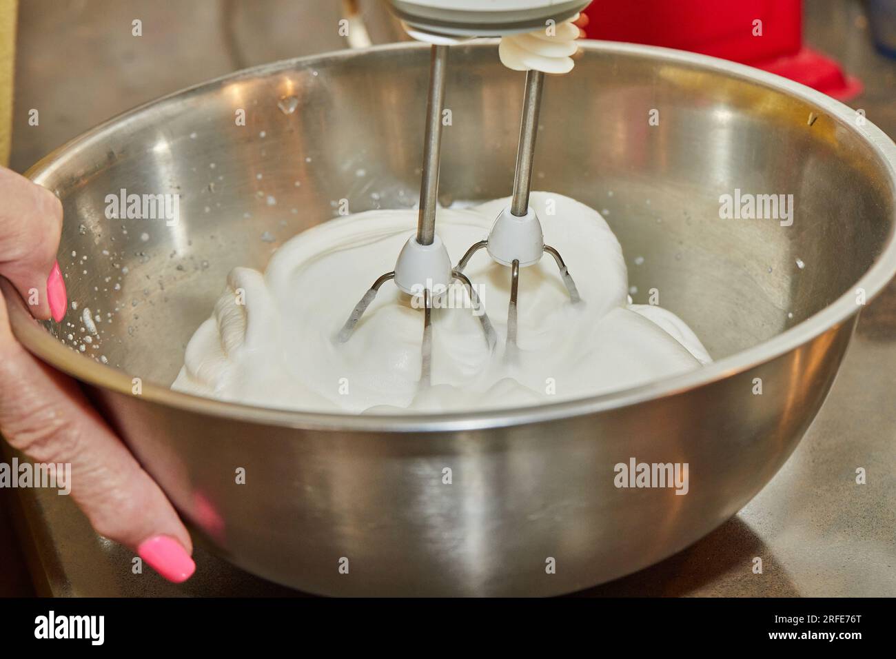 Der Koch peitscht Eiweiß mit einem Mixer in der Schüssel. Stockfoto