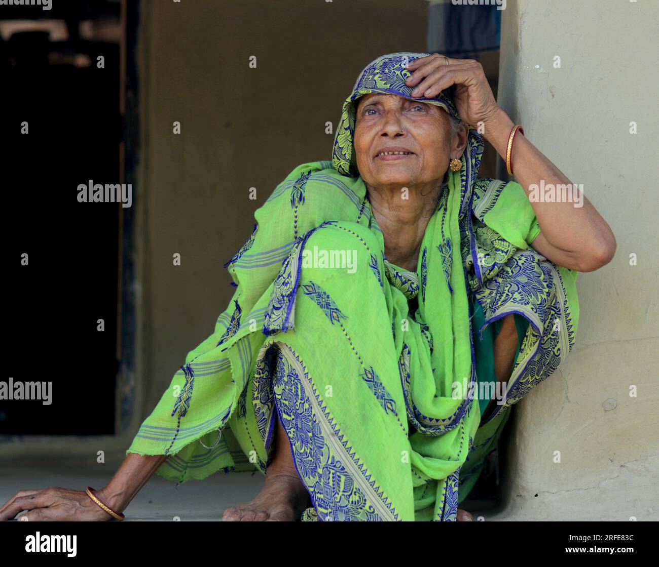 Eine 70-jährige Indianerin, die auf dem Boden mit grünem Saree saß. Ein normaler Tag im indischen Dorfleben. Stockfoto