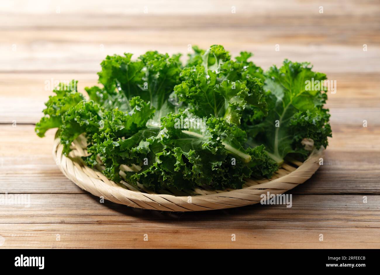 Grünkohl in einem Sieb vor einem Holzhintergrund. Grünkohl. Stockfoto