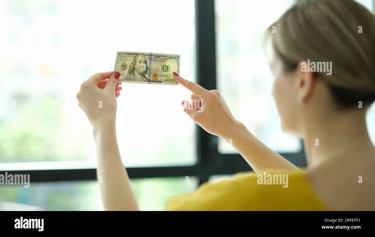 Gefälschter Scheck. 100 Dollar gegen ein Fenster in der Hand Stockfoto