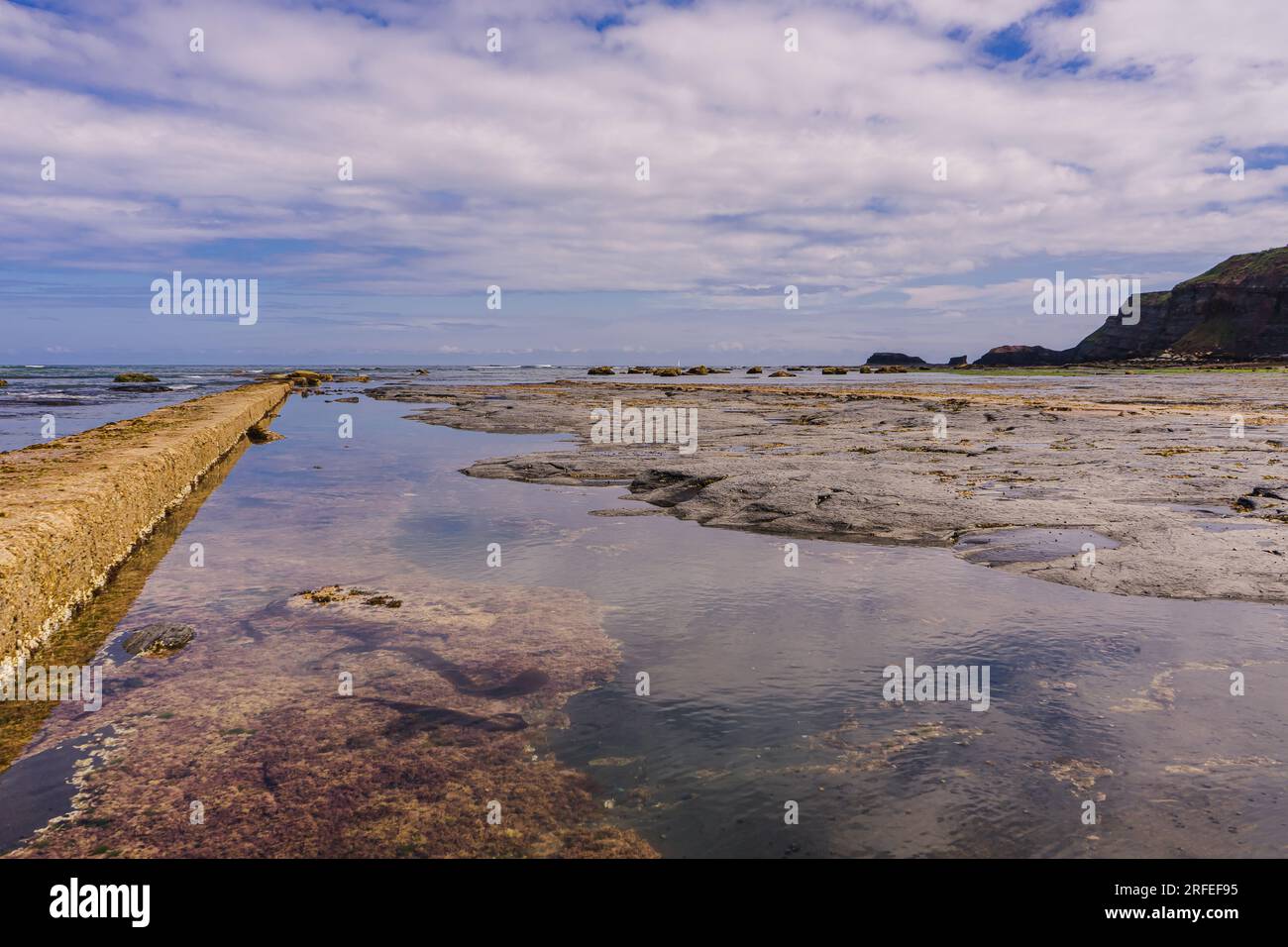 Bei Ebbe am East Beach in Whitby ist ein großer Bereich von flachen Felsen und Felsenbecken freigelegt. Dieses Foto wurde in Richtung Saltwick NAB - The WH gedreht Stockfoto