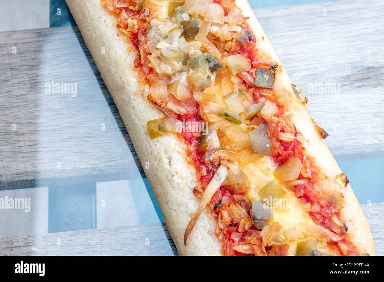 Hot Dog: Ein entzückender Hotdog gefüllt mit leckeren Gurken, gebratenen Zwiebeln und einem Hauch Tomatensoße, aufgenommen in einem köstlichen Foto von oben auf einem g. Stockfoto