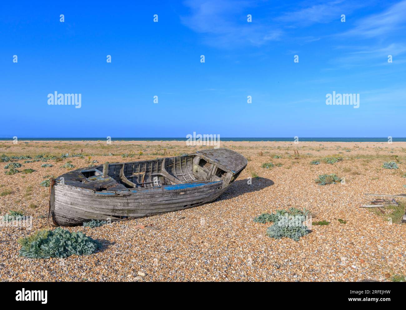 Ein Schiffswrackboot am Dungeness Beach an der Südküste Großbritanniens. Kilometerlanger Kieselstrand, isolierte, schwarz bemalte Hütten und ein Kraftwerk Stockfoto