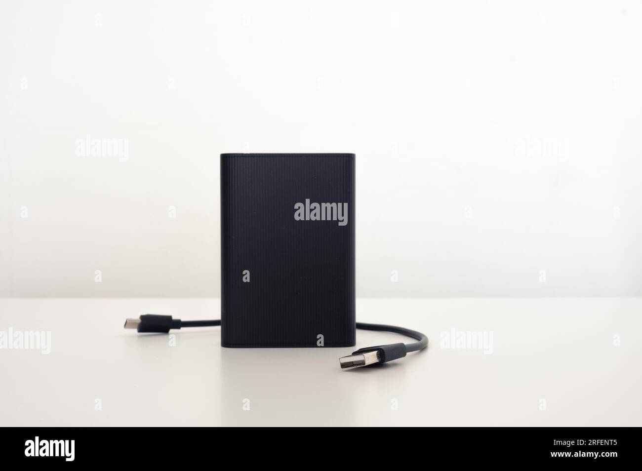 Tragbare schwarze Powerbank mit isoliertem USB-Kabel auf weißem Hintergrund Stockfoto