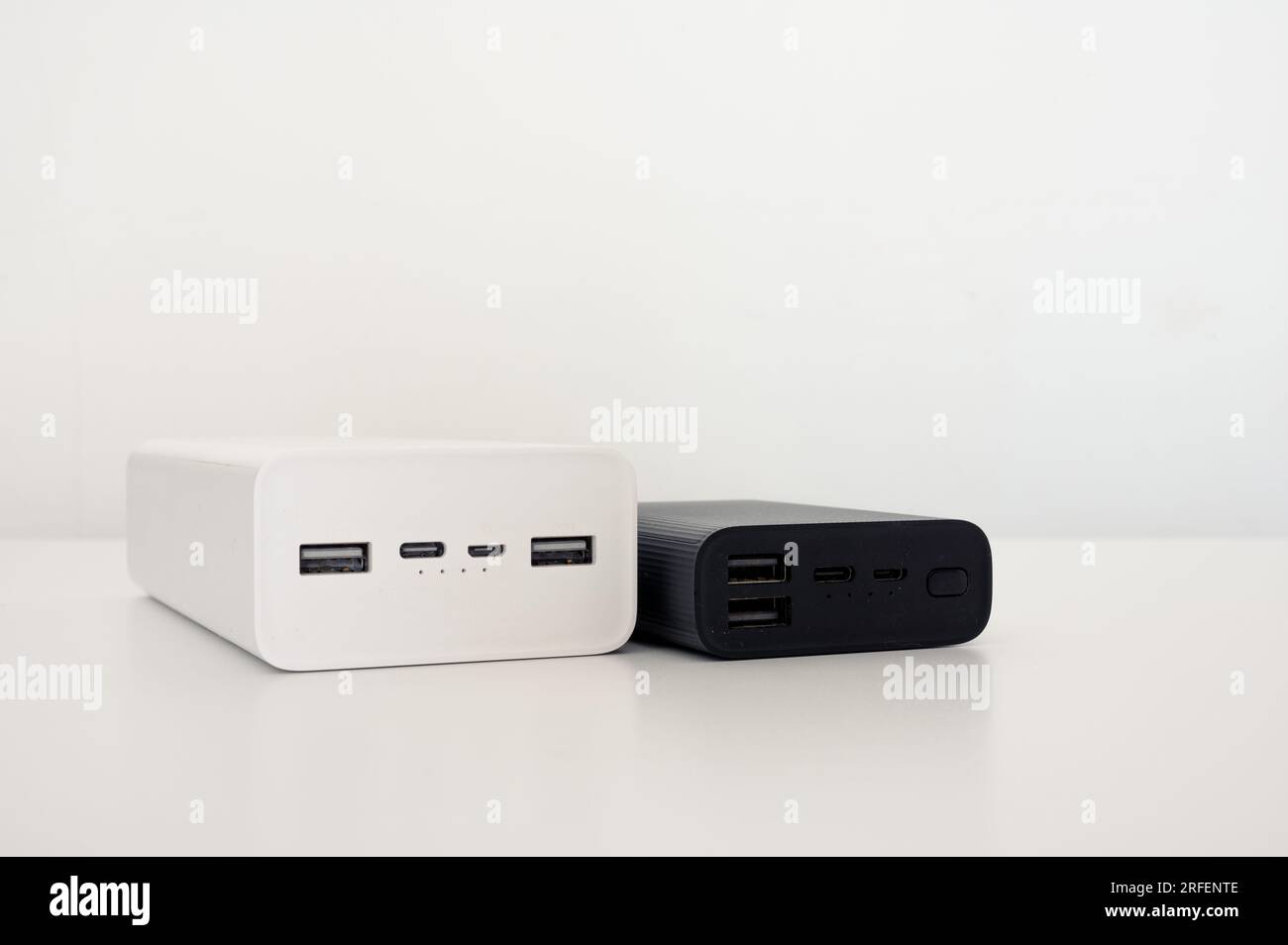 Weiße Powerbank und schwarzes mobiles Ladegerät auf dem Tisch. Weißer Hintergrund. Stockfoto