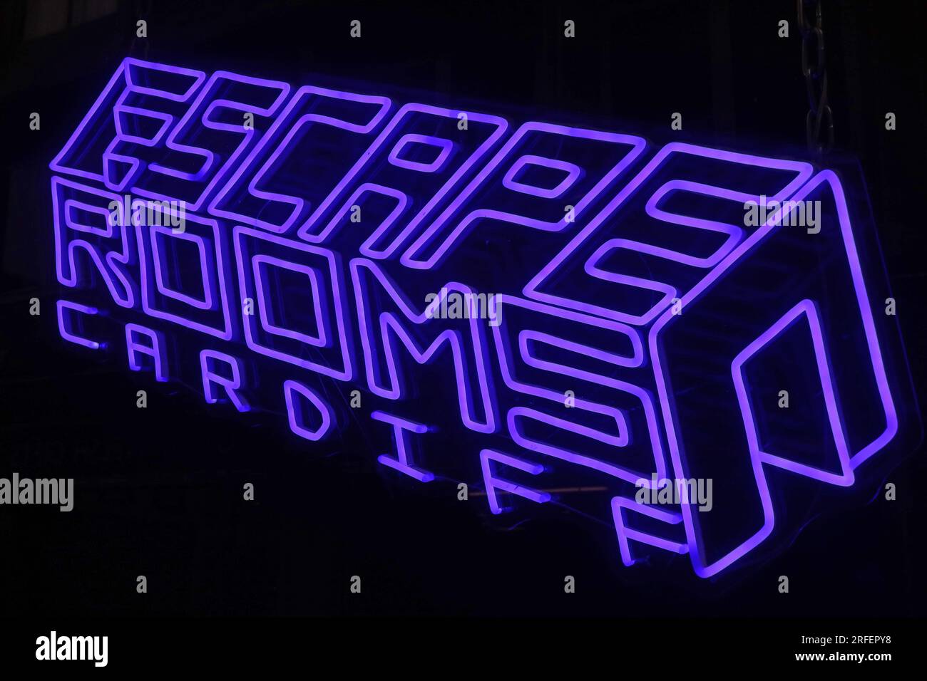 Violettes Neonschild mit der Aufschrift „Escape Rooms Cardiff“, beleuchtet vor dunklem Hintergrund, Cardiff, Wales, Großbritannien. Stockfoto