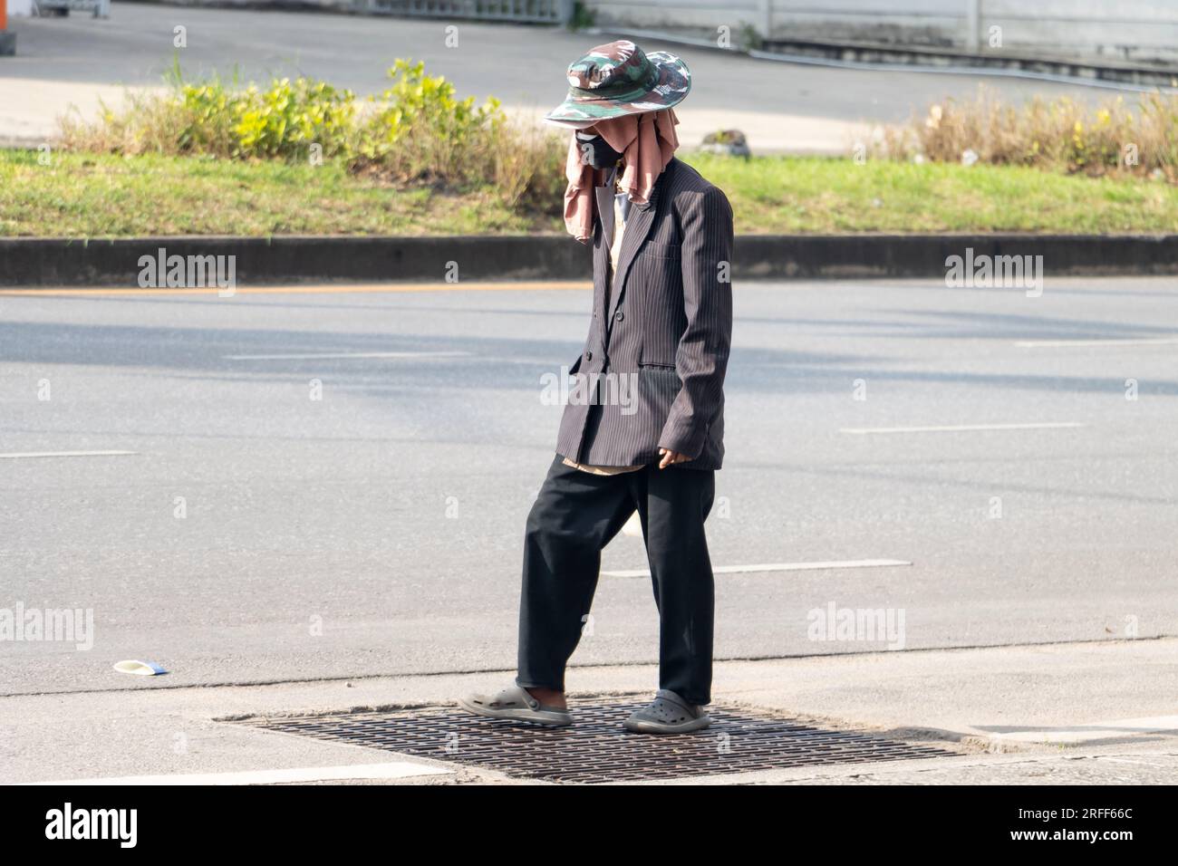Ein Mann mit einem bedeckten Kopf geht die Straße runter, Thailand Stockfoto