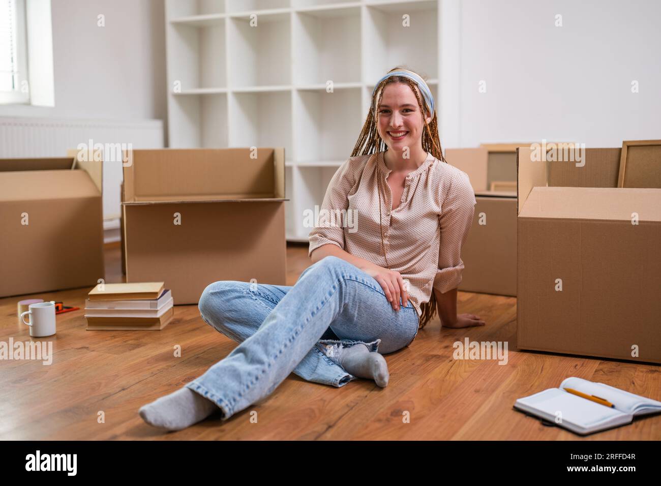 Moderne Ingwerfrau mit Zöpfen zieht in neue Wohnung. Stockfoto