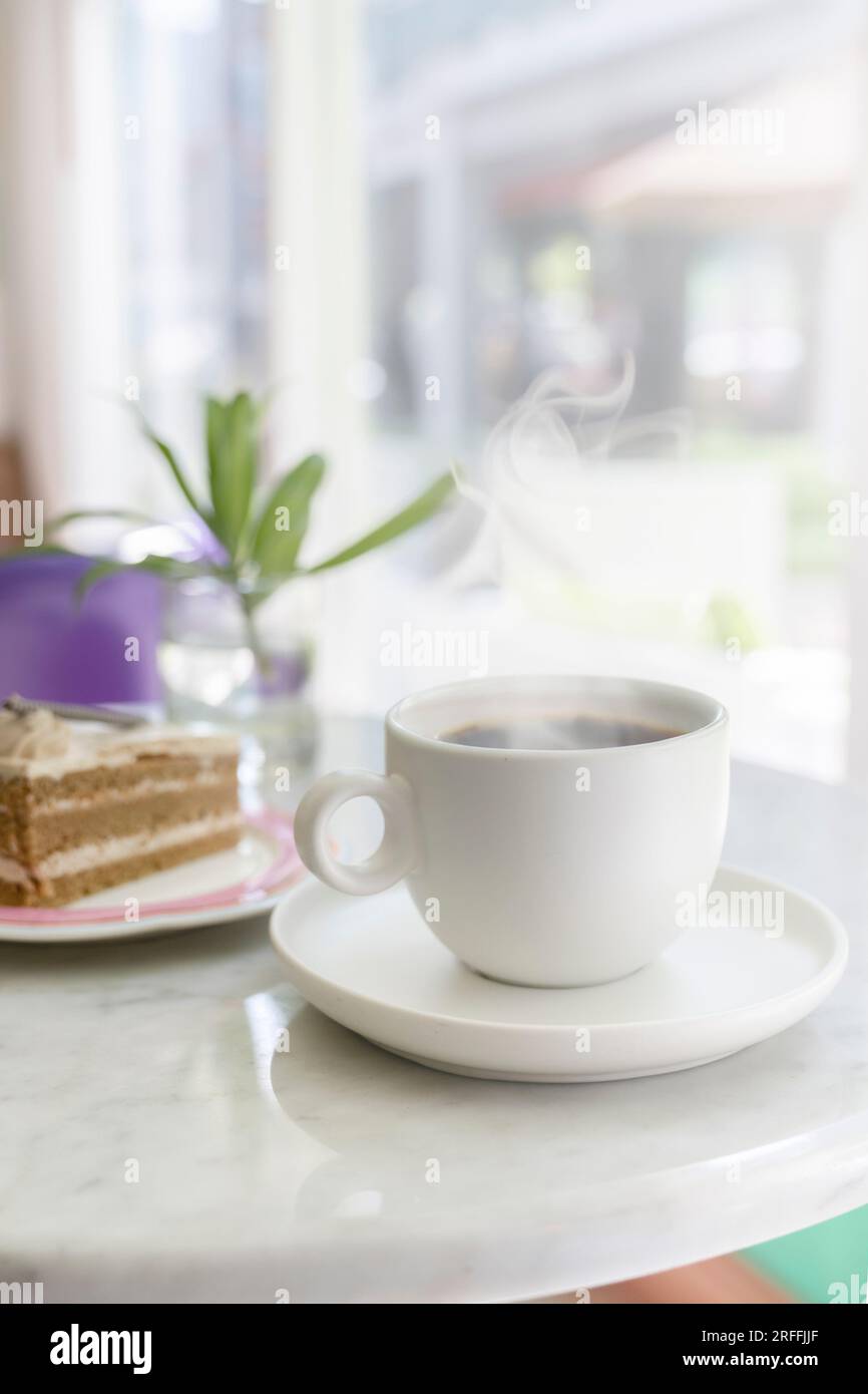 Kaffeepause. Eine Tasse heißen, dampfenden Kaffee auf dem Tisch, neben einem Kuchen. Konzept für einen Coffeeshop. Stockfoto