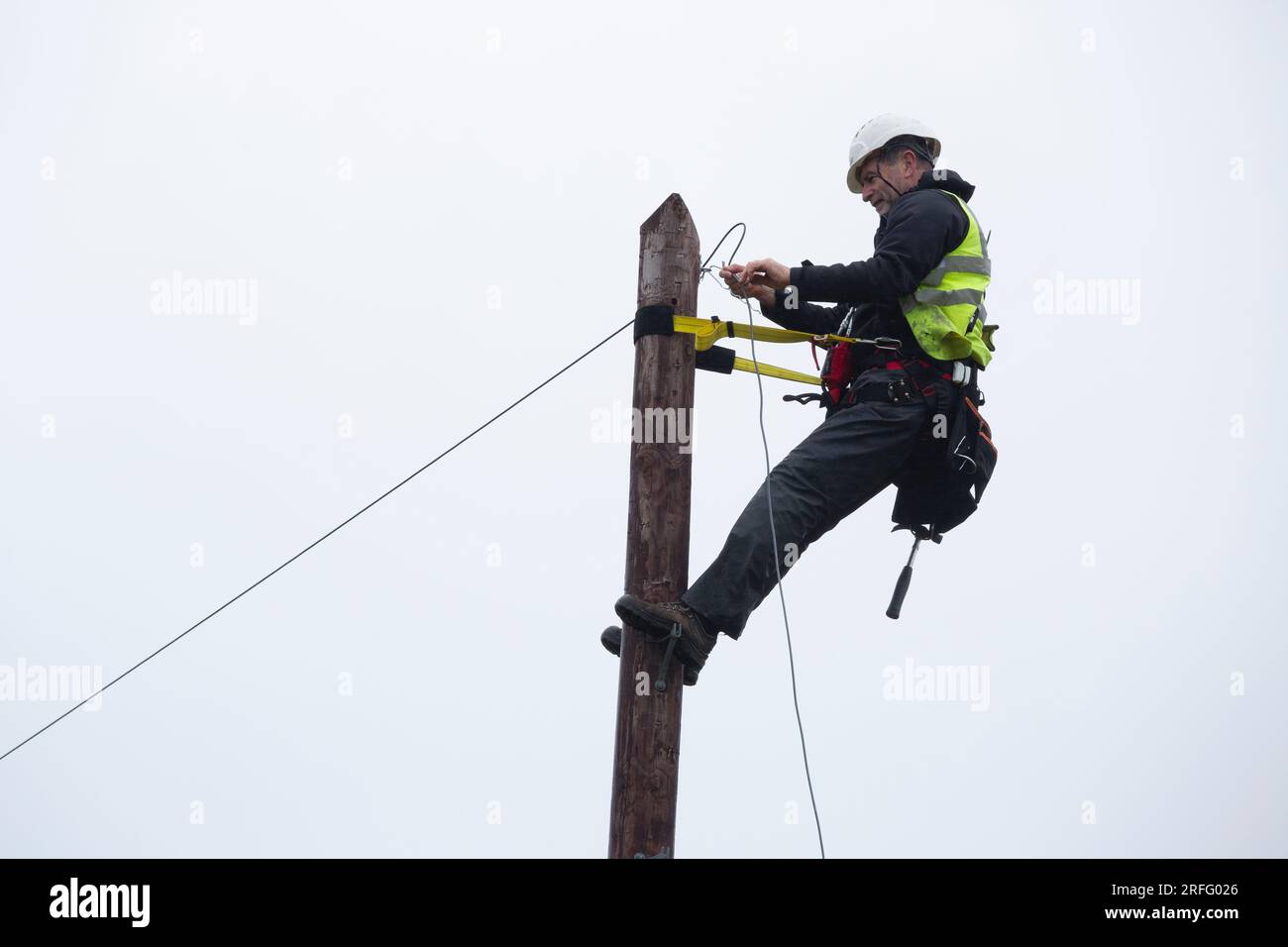 Techniker, der ein Breitband-Glasfaserkabel an einen Pol anschließt Stockfoto