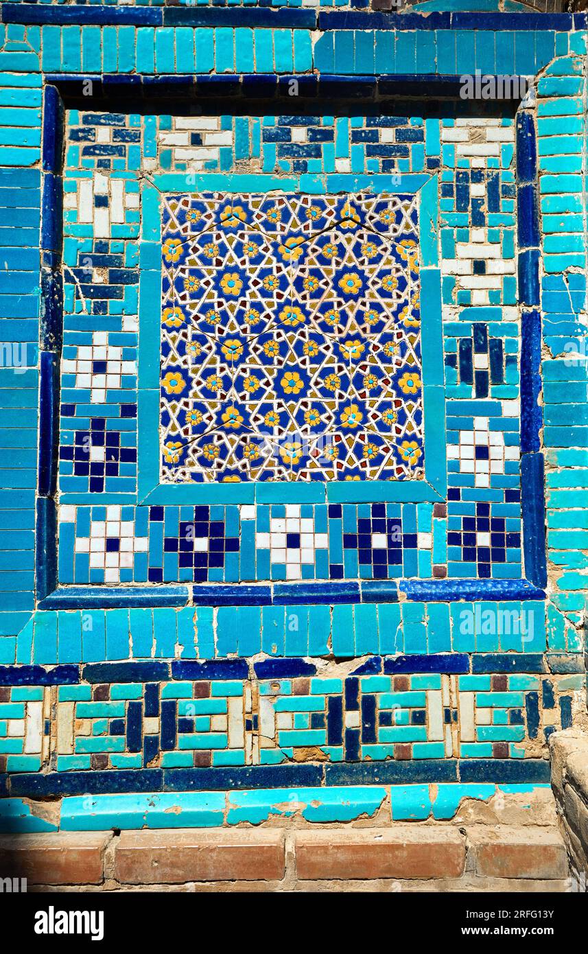 Mosaik an der Wand des wunderschönen historischen Friedhofs Shahi Zinda mit Wand und Bogen, die von blauen und türkisfarbenen Steinmosaiken mit Mausoleen i geschmückt sind Stockfoto