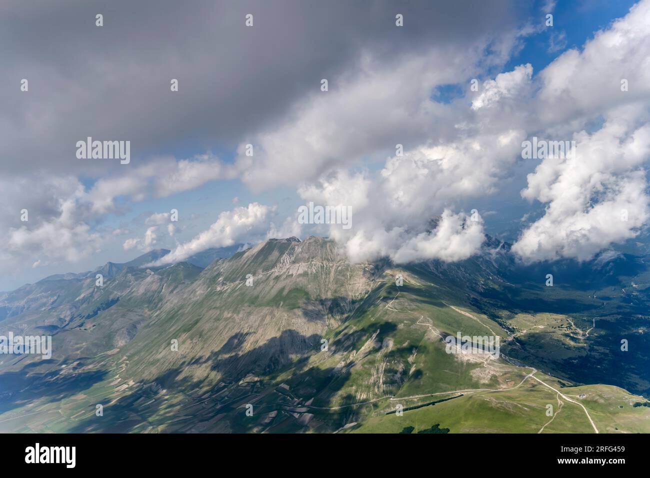 Luftlandschaft aus einem Segelflugzeug mit kargen Hängen des Vettore Peak, umgeben von Wolken der Meeresbrise, die von Südwesten im hellen Sommerlicht aufgenommen wurden Stockfoto