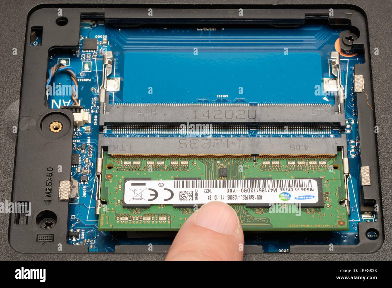 Sichern eines typischen RAM-Speichermoduls nach dem Einsetzen in einen Speichersockel in einem Laptop. Der Finger drückt nach unten, um das Modul in den Clips einrasten zu lassen. (3 von 4) Stockfoto