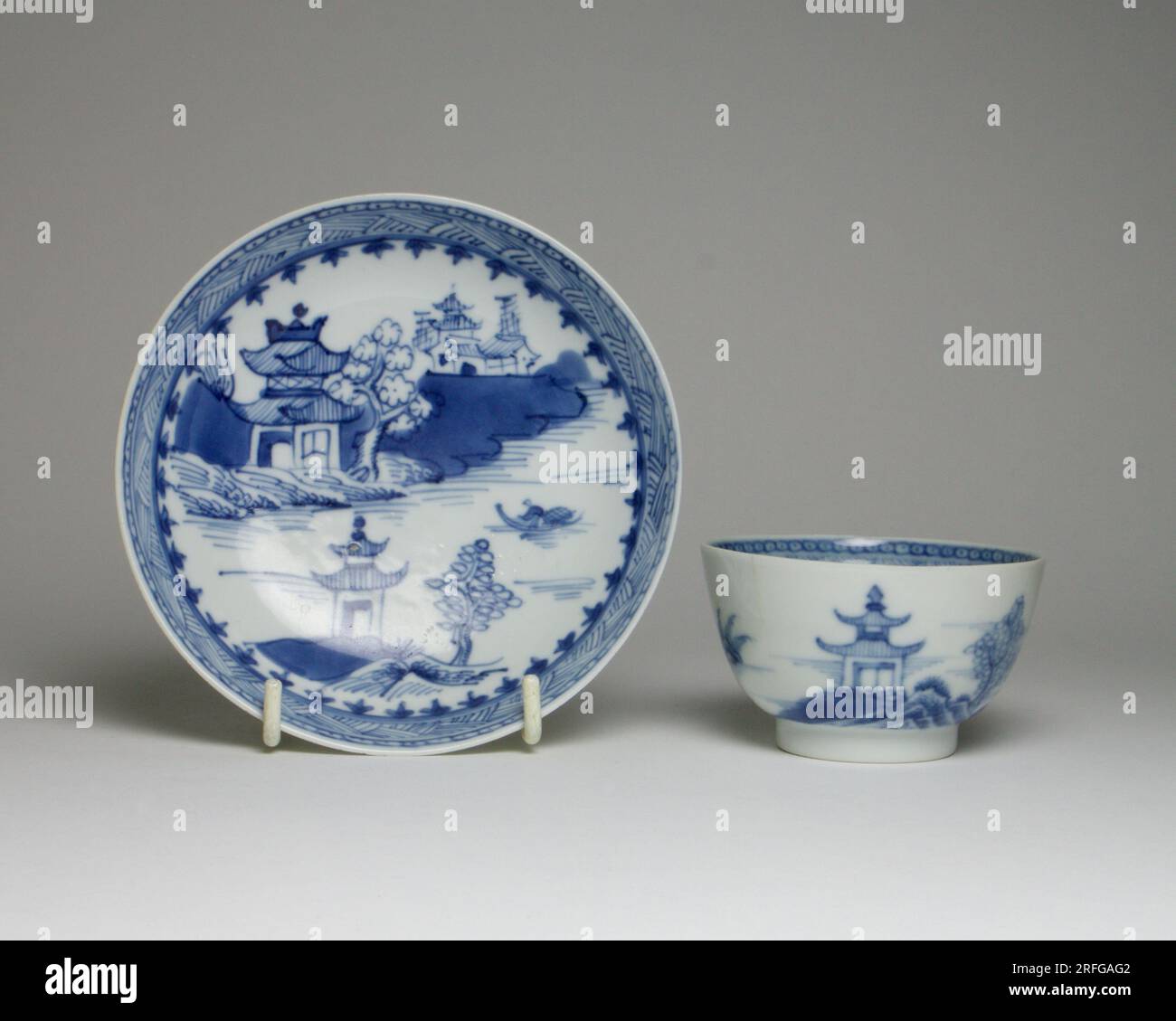 Antike Teeschale und Untertasse aus blauem und weißem Porzellan aus dem 18. Jahrhundert, handbemalt mit Pagoden am Ufer eines Sees. Die Untertasse misst ca. Stockfoto