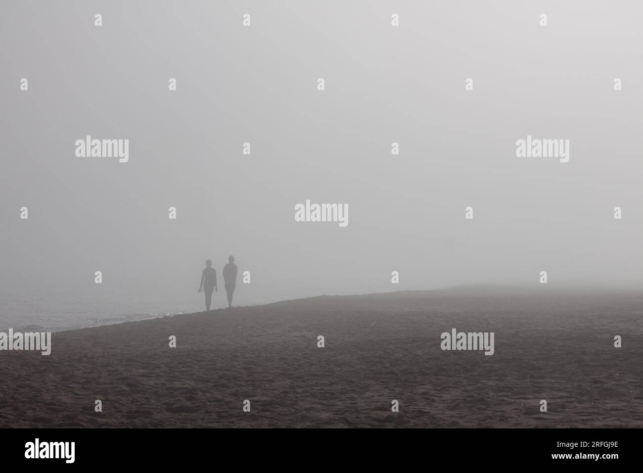 Strand mit Nebel und Silhouette von unbekannten Menschen Stockfoto