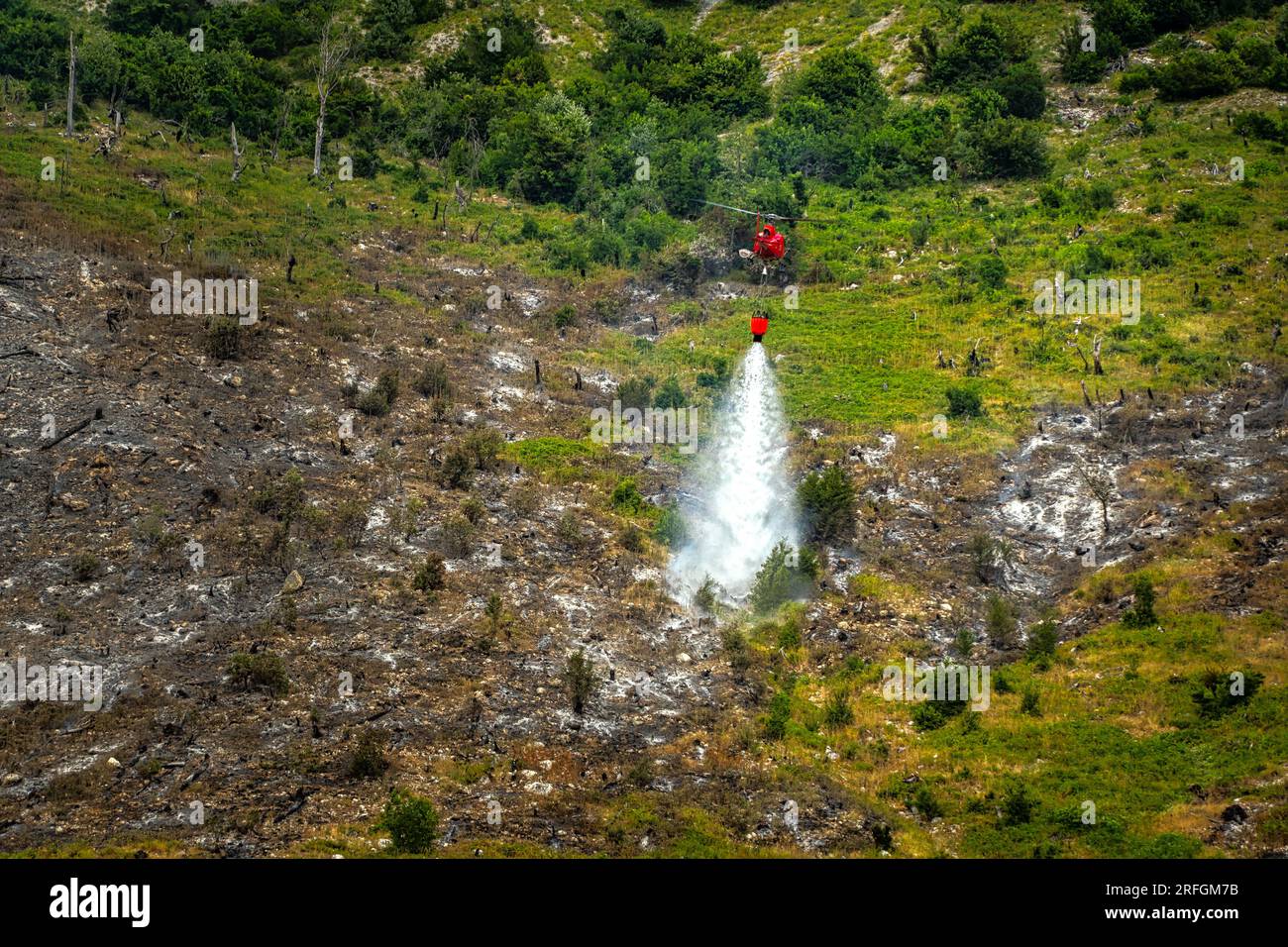 Dramatische Szene mit Flammen und Rauch von einem Waldbrand. Der Katastrophenschutz-Helikopter bekämpft die Flammen mit dem Wasser Monte Morrone, Maiella-Nationalpark Stockfoto