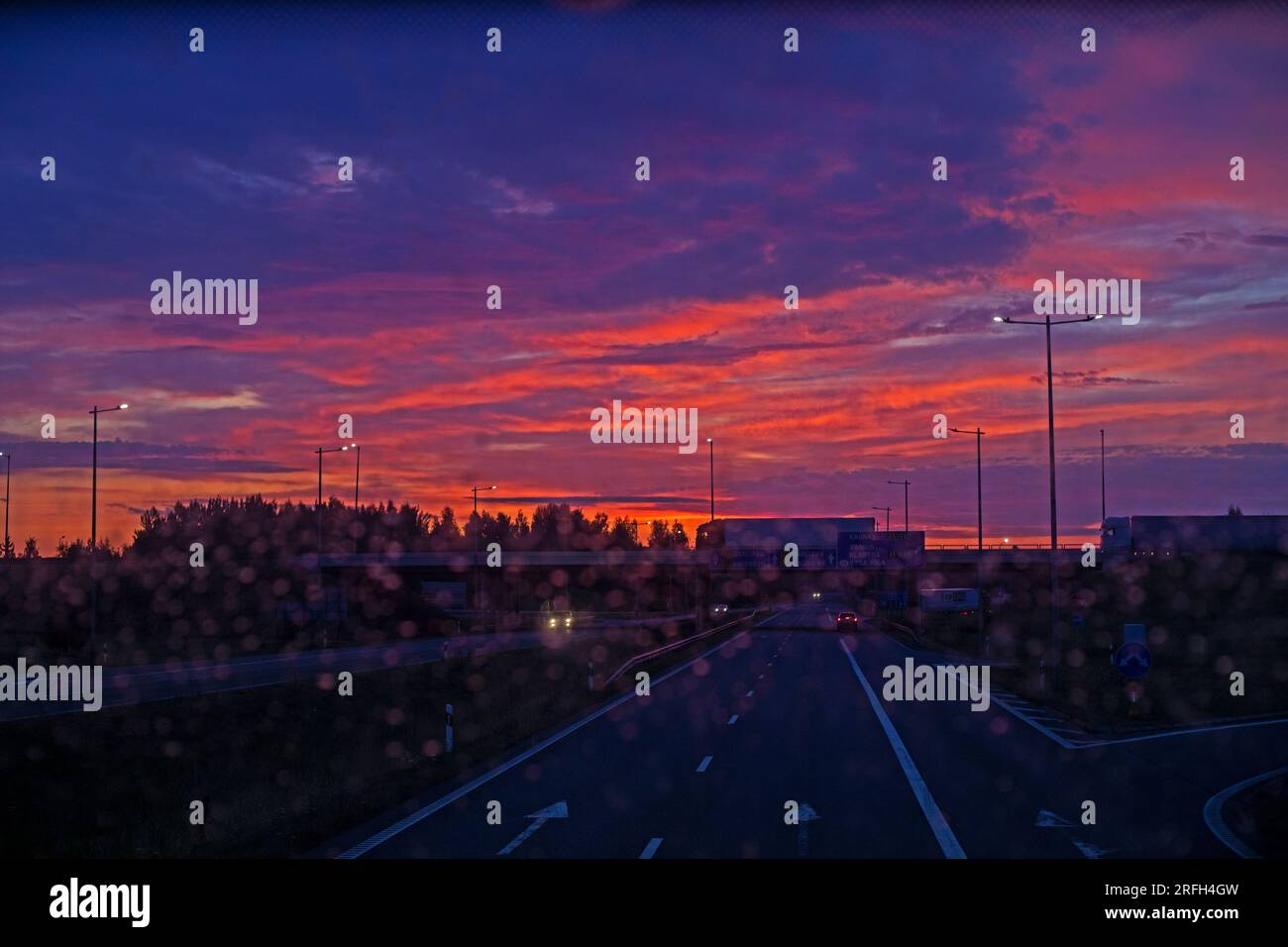 Verschwommener Sonnenaufgang auf dem Highway durch das schmutzige Glas des Busses. Stockfoto