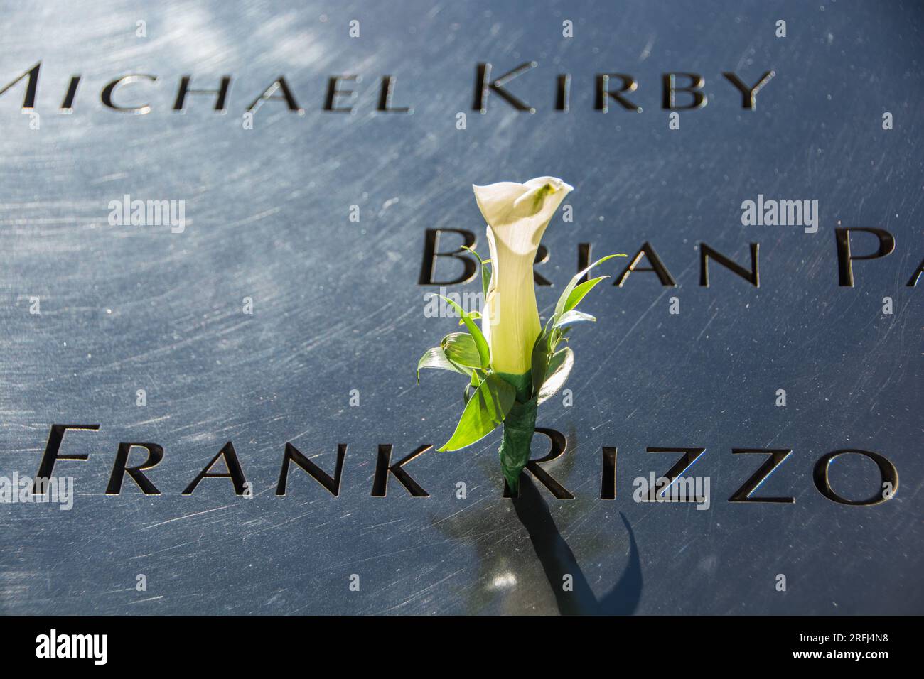 Namensaufzählung mit Blume der Opfer bei den Terroranschlägen vom 11. September 9/11 auf der Gedenkstätte am 11. September 9/11 mit Bäumen in Herbstfarbe im Hintergrund. Stockfoto