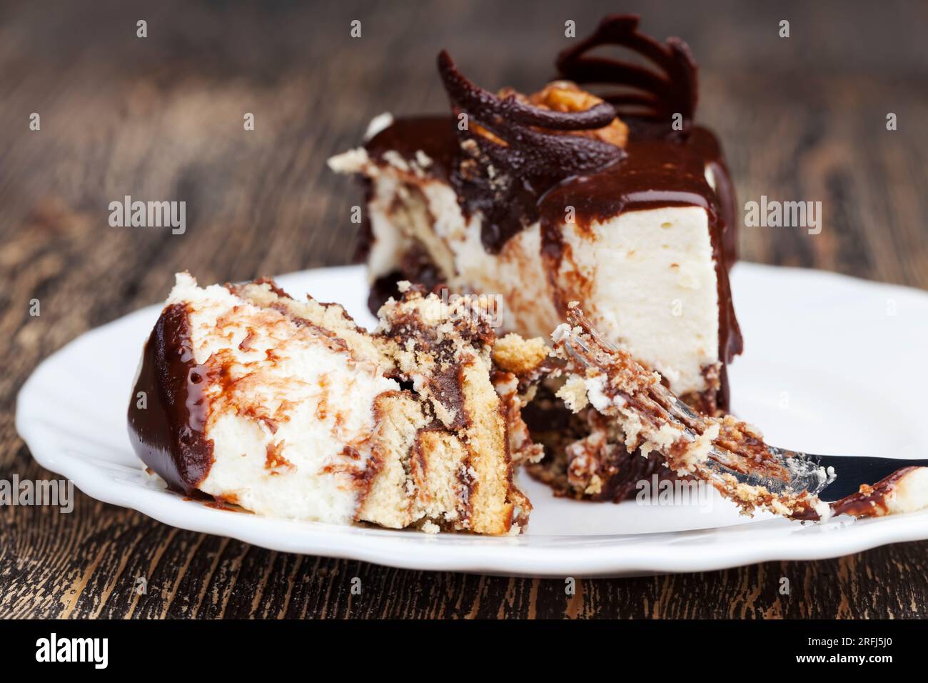 Schokoladencreme-überzogener Cremetorte mit Biskuitkuchen, würfelförmiger Kuchen auf einem Teller Stockfoto