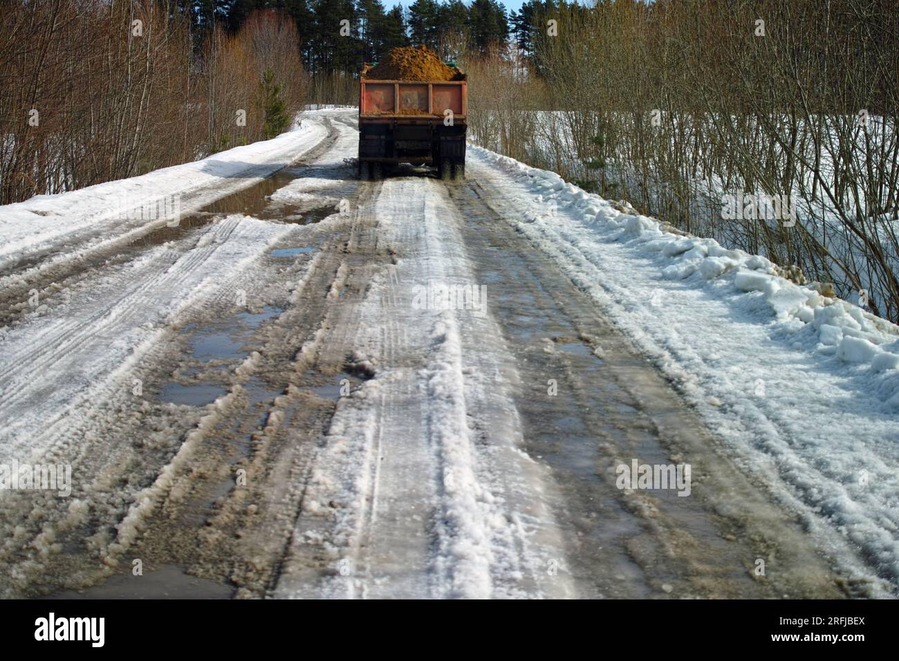 Leicht fokussiertes Bild eines mit Sand beladenen Lkws auf der rutschigen Straße Stockfoto