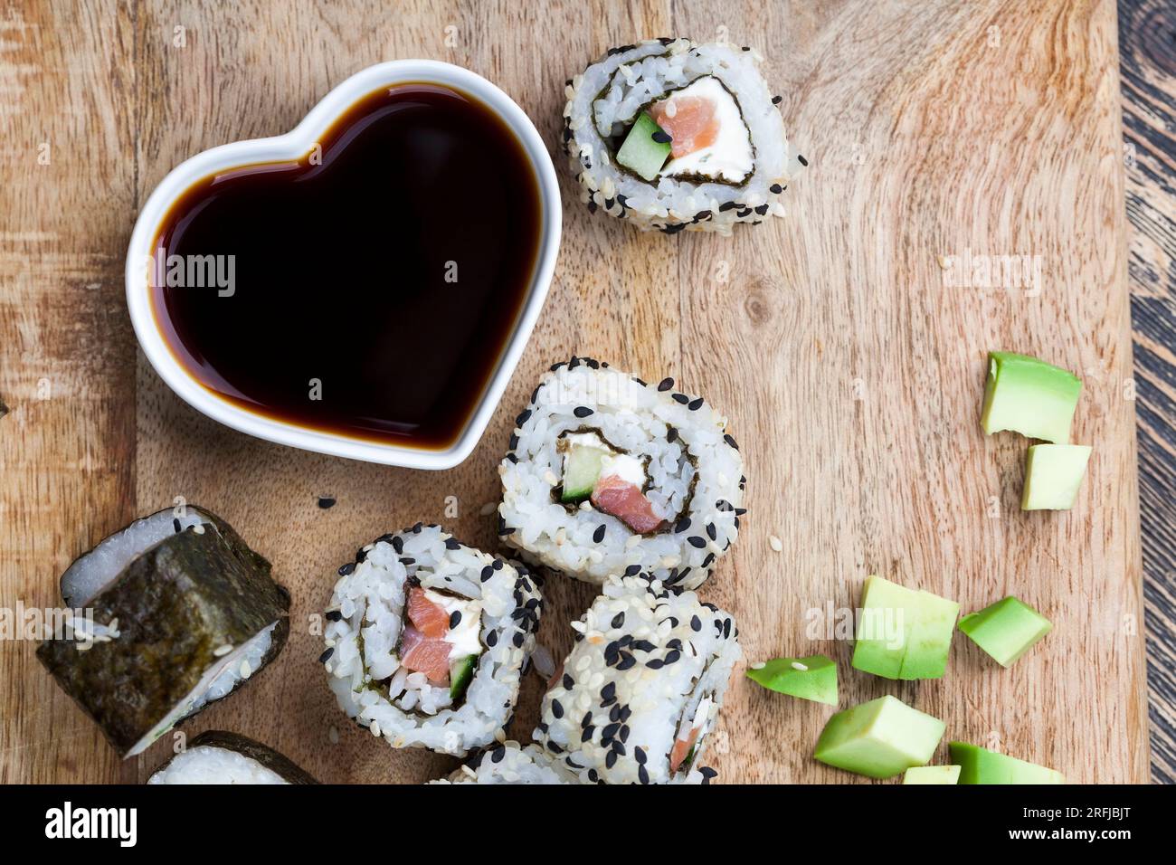Sushi aus weißem Reis, Forelle und Avocado, verzehrfertige pflanzliche Produkte und roter Fischlachs Stockfoto