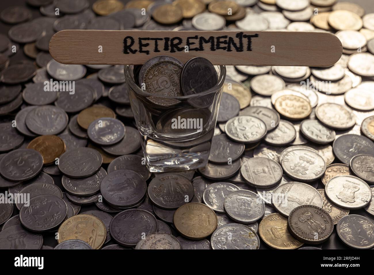 Eine Nahaufnahme indischer Rupien-Münzen auf einem Tisch. Das Wort "Ruhestand" steht auf einem Stock auf dem Tisch Stockfoto