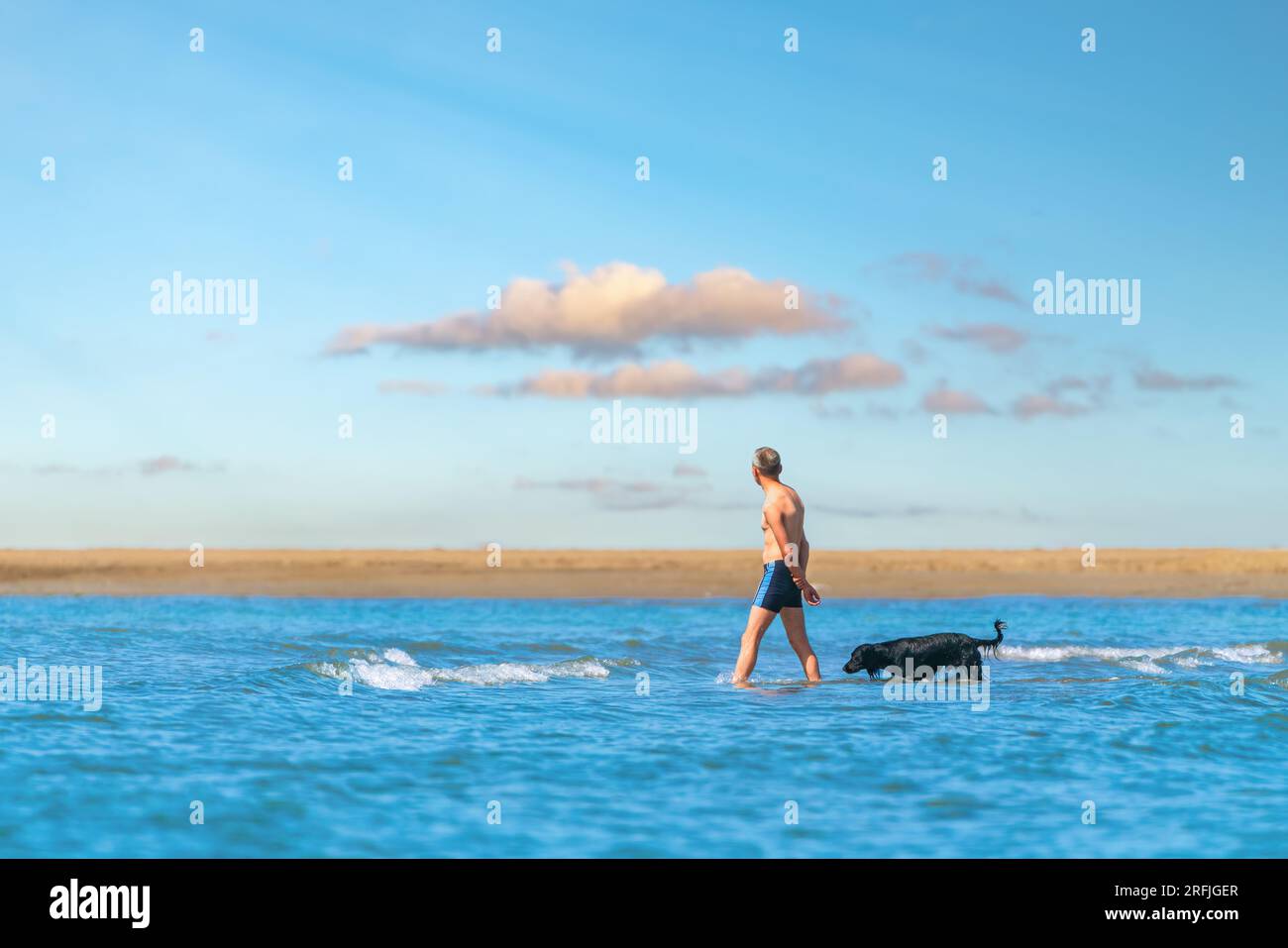 Mann mit Hund, der am Meer vorbeiläuft Stockfoto