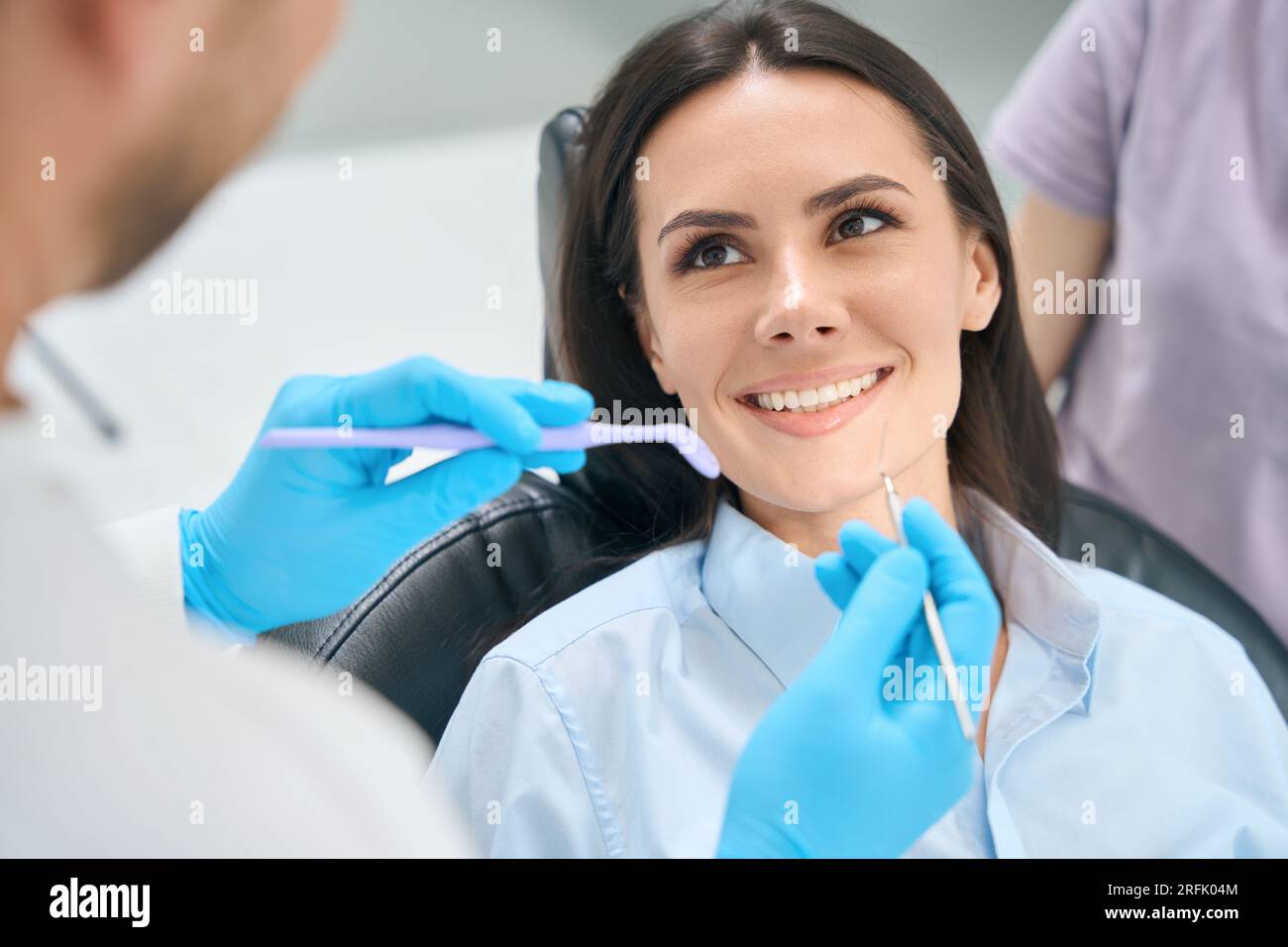 Männlicher Zahntechniker, der spezielle medizinische Werkzeuge wie Mundspiegel und Sichelsonde verwendet, um die Gesundheit von weiblichen Zähnen und Zahnfleisch zu überprüfen, Routineuntersuchungen Stockfoto