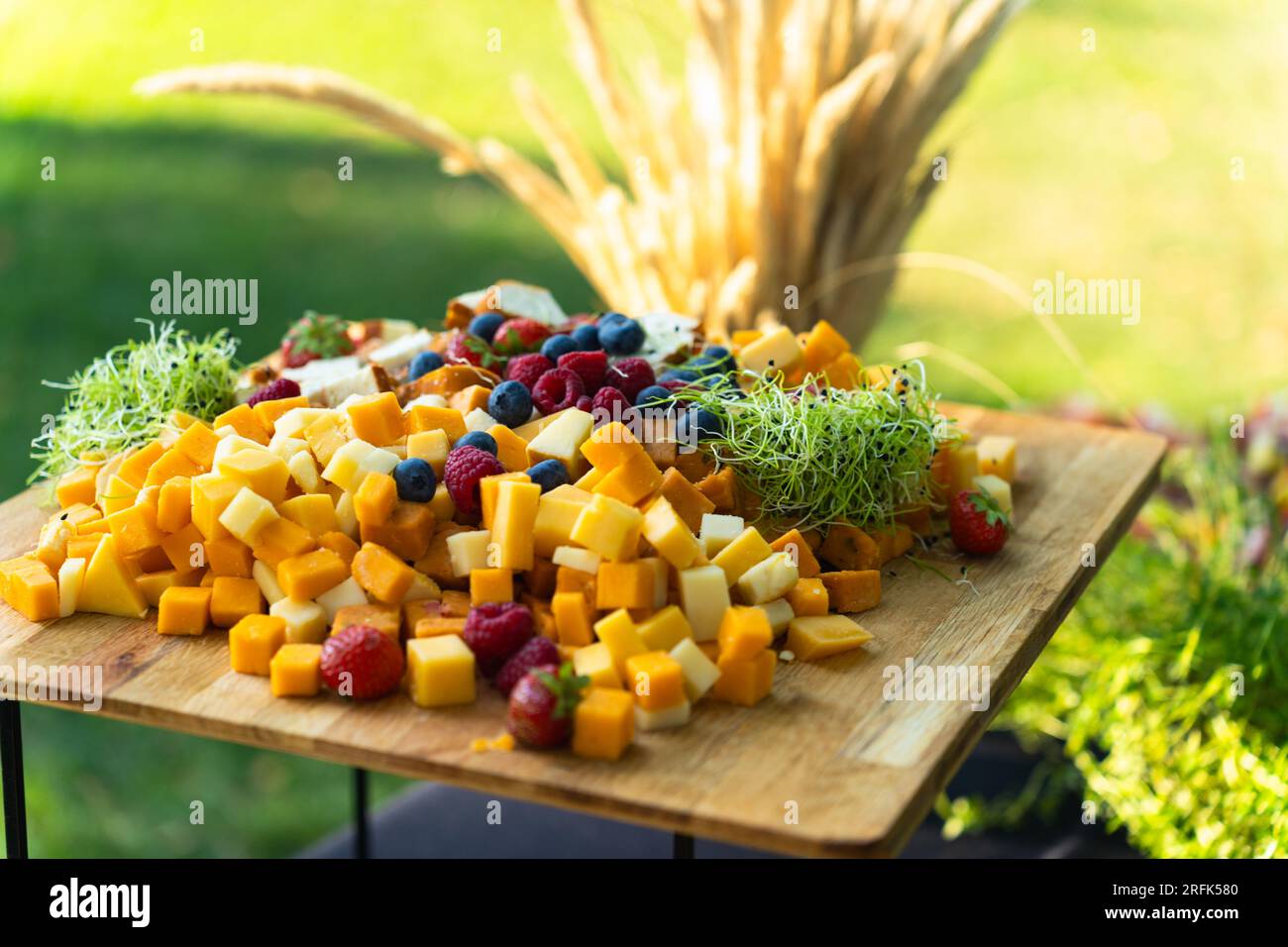 Gehen Sie an Bord mit verschiedenen Käsesorten und Früchten, die im Sommer für ein Buffet im Hof zubereitet werden Stockfoto