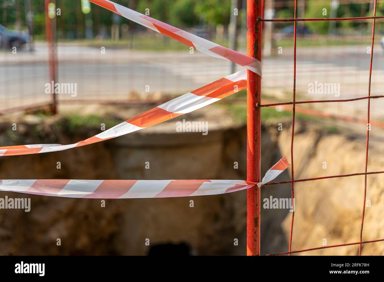 Der Reparaturort auf der Straße der Stadt ist mit einem rot-weißen Signalband eingezäunt. Reparaturarbeiten an kommunalen Versorgungsbetrieben. Sturzgefahr Stockfoto