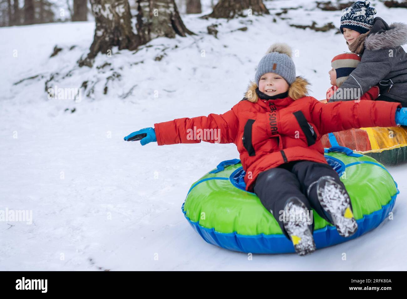 Süße weiße Jungs, die im Winterpark auf Snow Tubing fahren. Bild mit selektivem Fokus Stockfoto