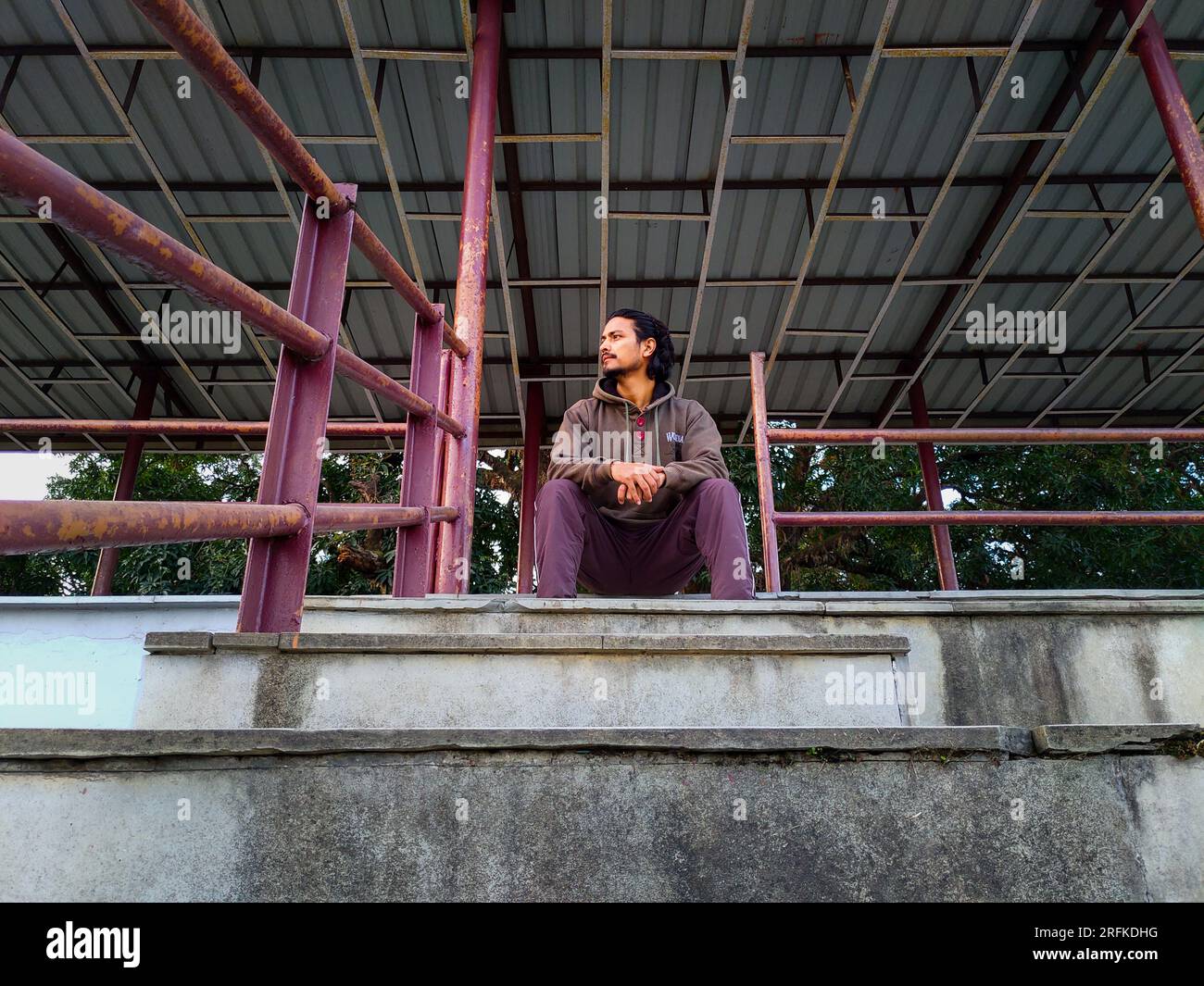 Oktober 14. 2022 Uttarakhand, Indien. Ein junger Indianer sitzt allein auf Stadionständen in Dehradun City, Indien. Ich denke an die Einsamkeit in der leeren Arena. Stockfoto