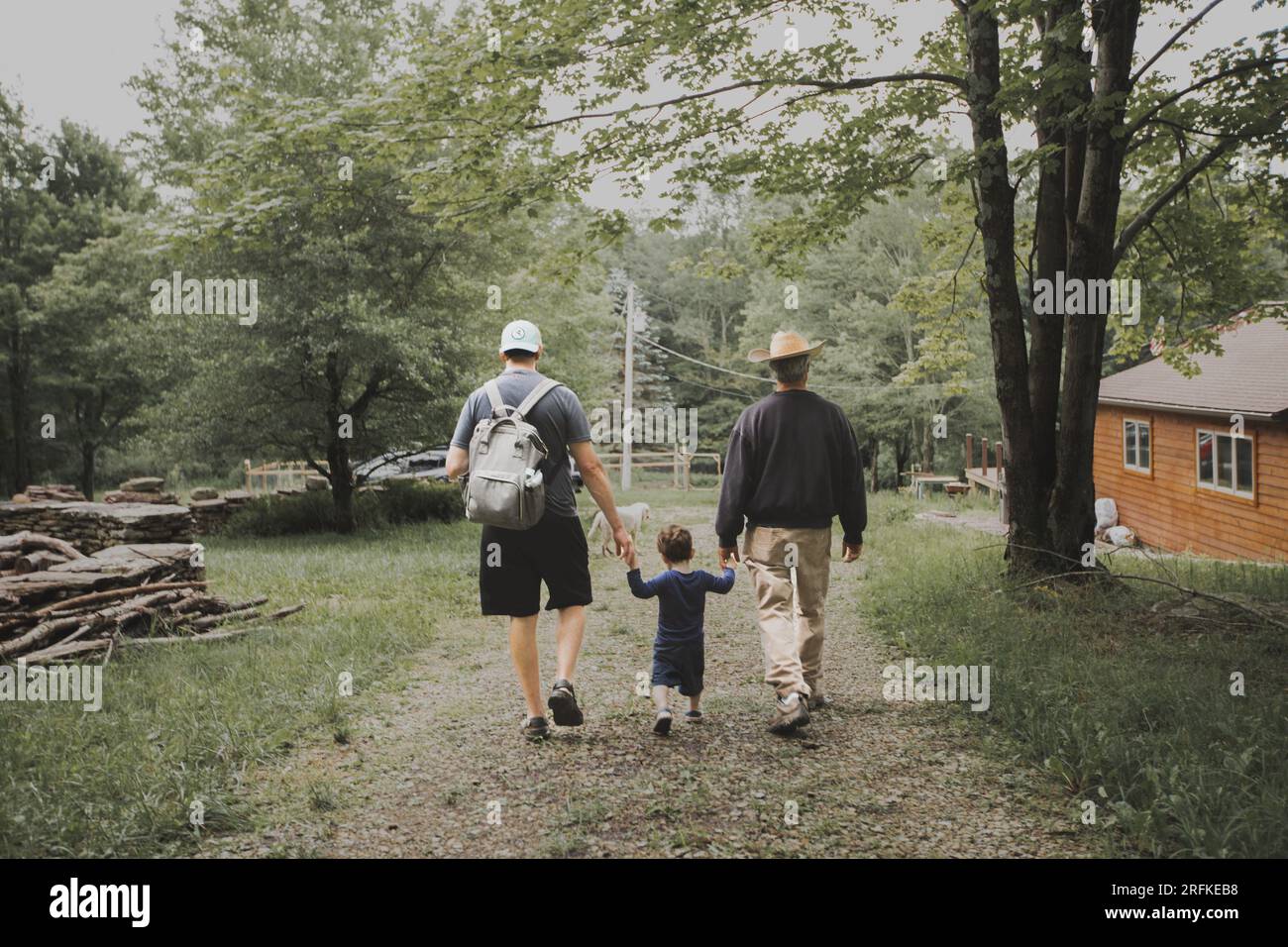 Ein Junge, der mit Vater und Großvater in der Nähe von Cabin Händchen hält Stockfoto