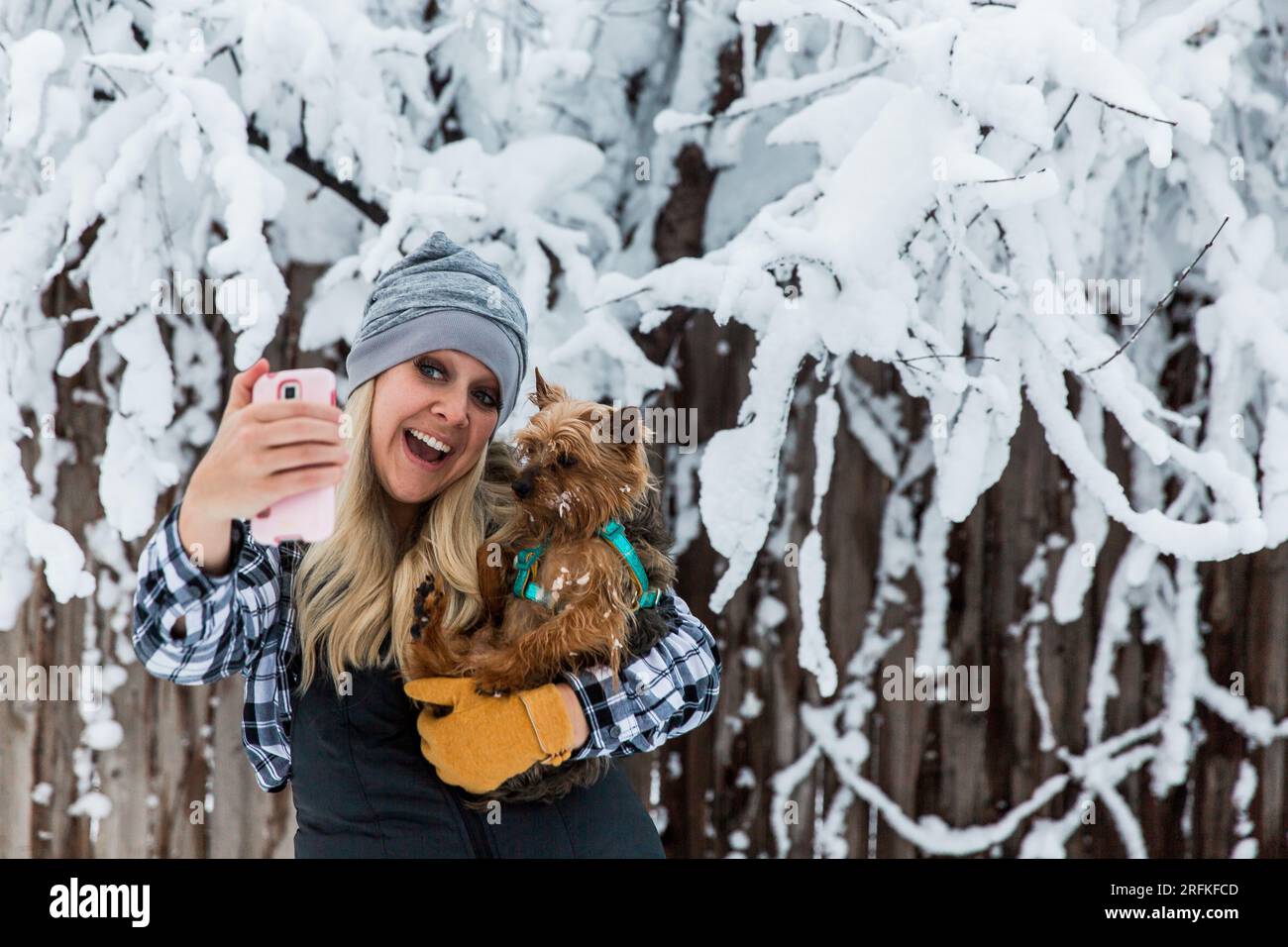Frau macht Selfie mit Hund an einem verschneiten Tag Stockfoto