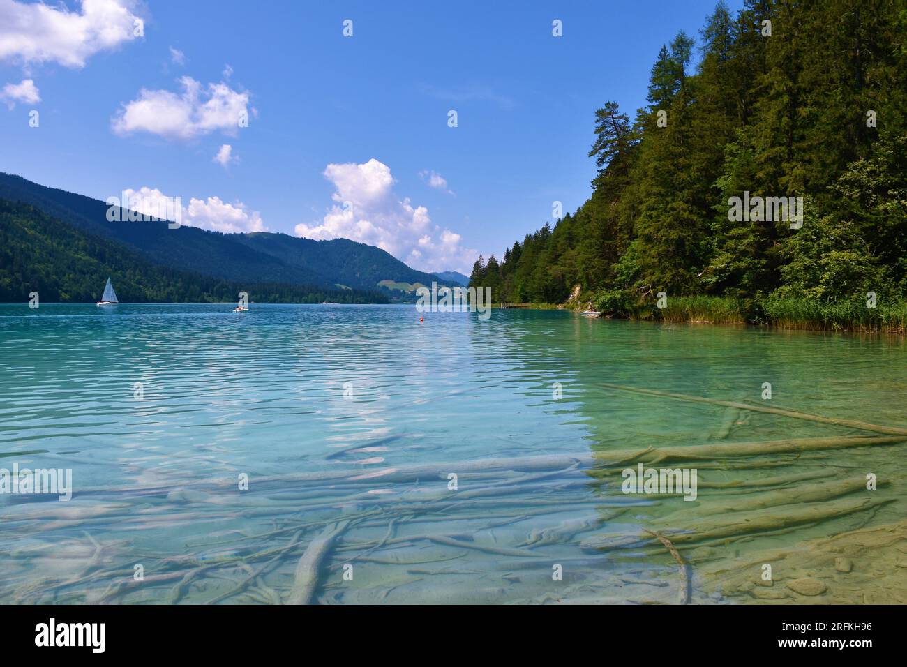 Weissensee in Kärnten oder Kärnten, Österreich mit waldbedeckten Hügeln und Booten auf dem See Stockfoto