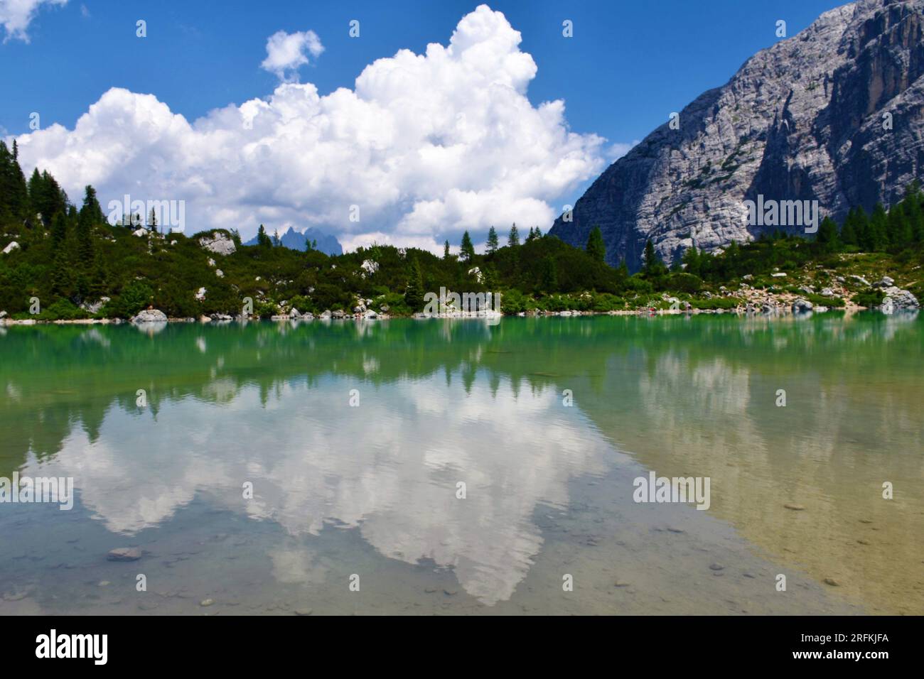 Blick auf den Sorapis-See in den Dolomiten in der Nähe von Cortina d'Ampezzo in der Region Venetien und der Provinz Belluno in Italien mit einer Reflexion der Wolken und des Strauchs Stockfoto