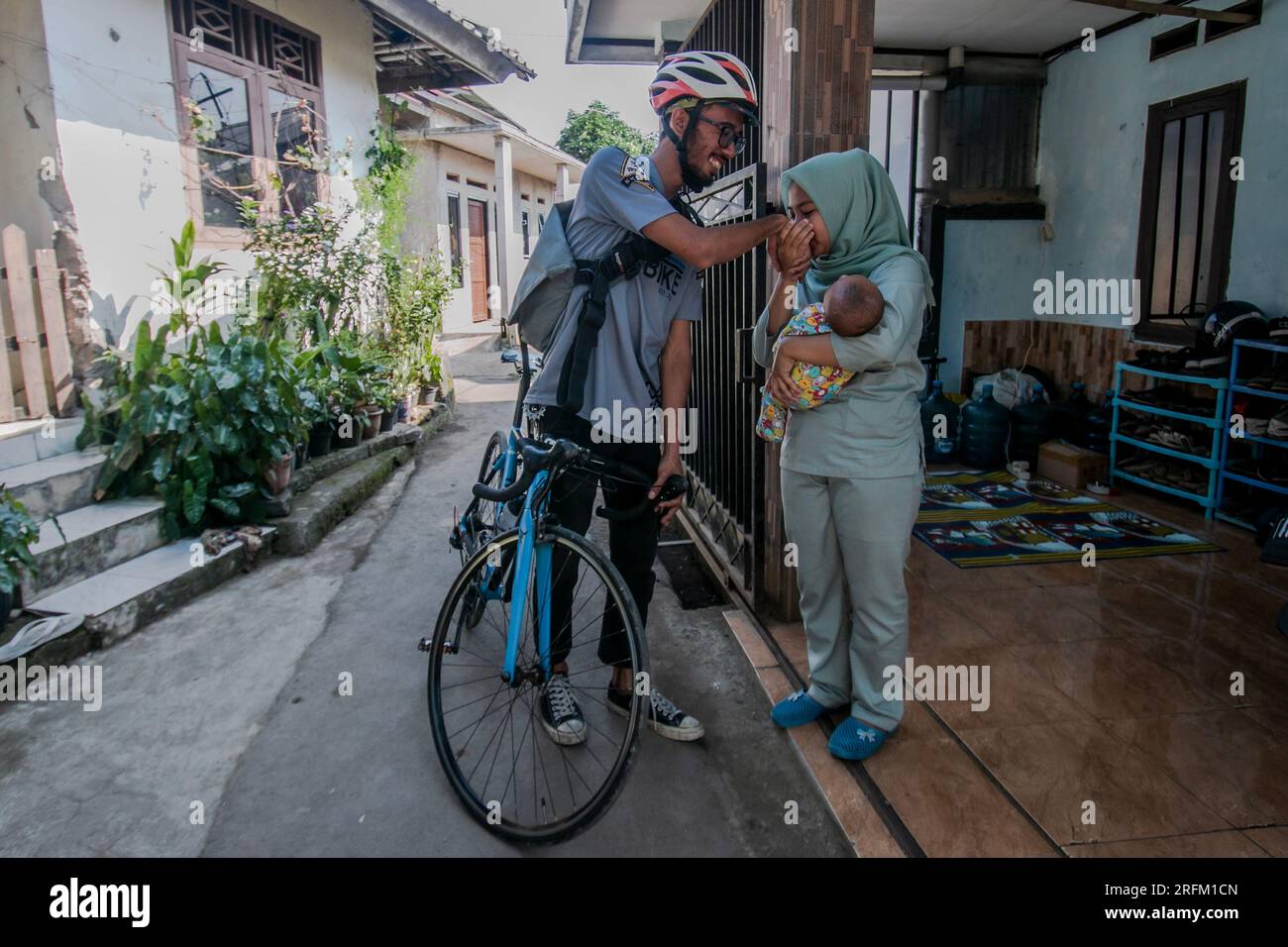Bogor, Indonesien - 01. August 2023: Ehemann verabschiedet sich von seiner Frau und seinem Baby, um in Bogor, West-Java, zur Arbeit zu gehen. Stockfoto