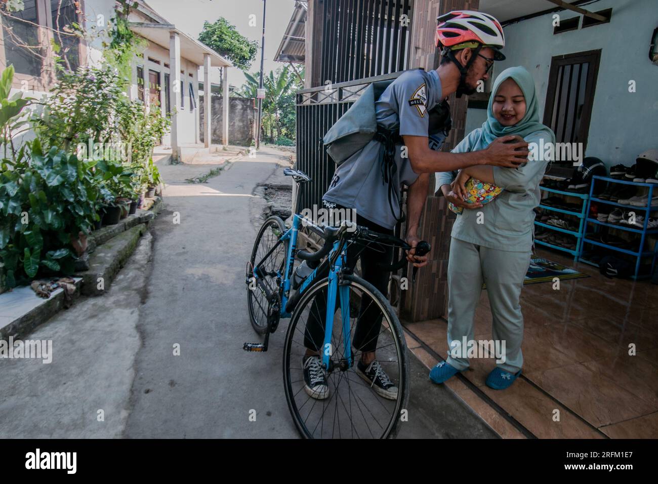 Bogor, Indonesien - 01. August 2023: Ehemann verabschiedet sich von seiner Frau und seinem Baby, um in Bogor, West-Java, zur Arbeit zu gehen. Stockfoto