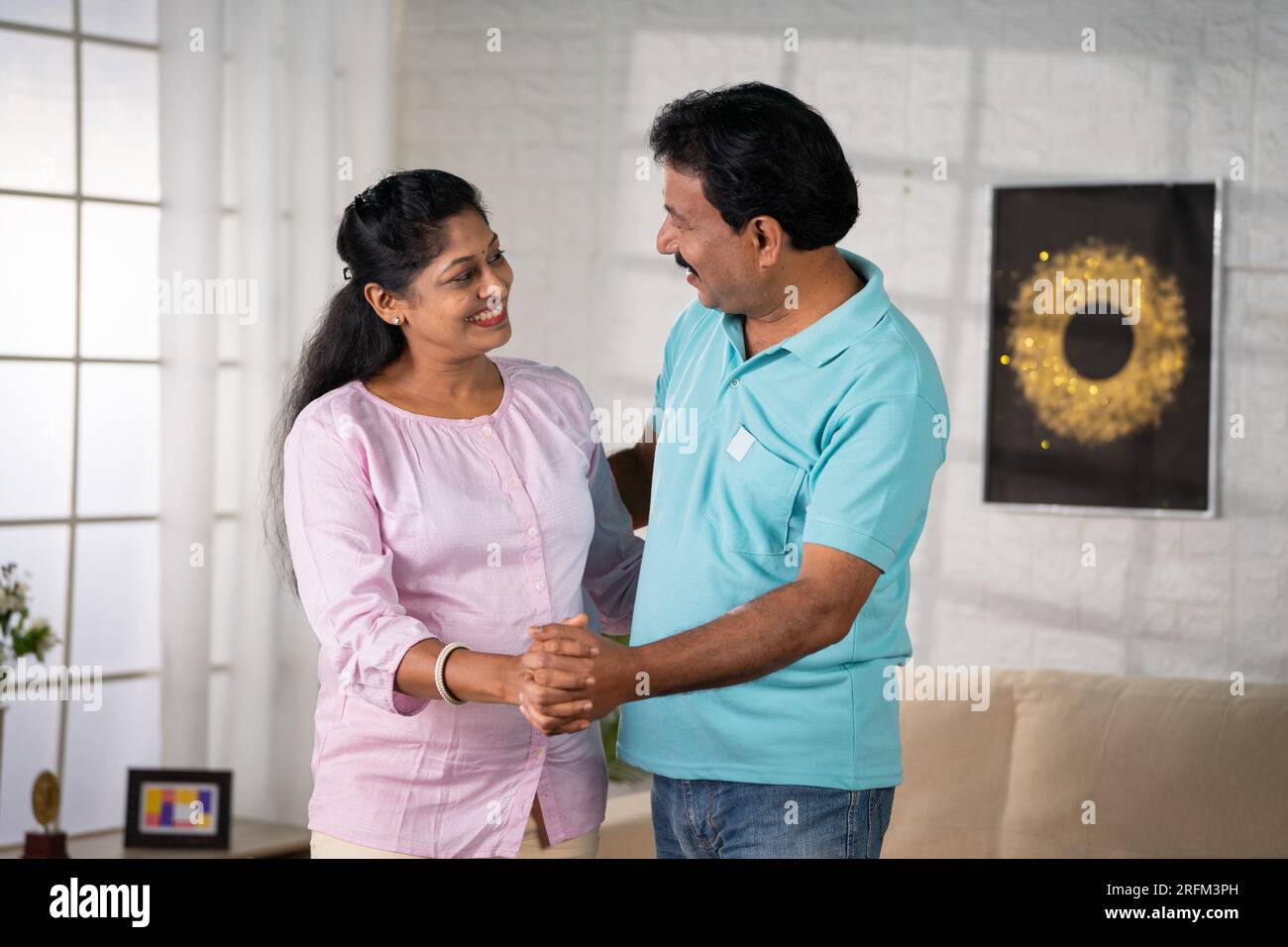 Fröhliches indisches Paar mittleren Alters, das zu Hause Hand in Hand tanzt - Konzept von liebevoller Bindung, romantischem Tanz und Happy Life. Stockfoto
