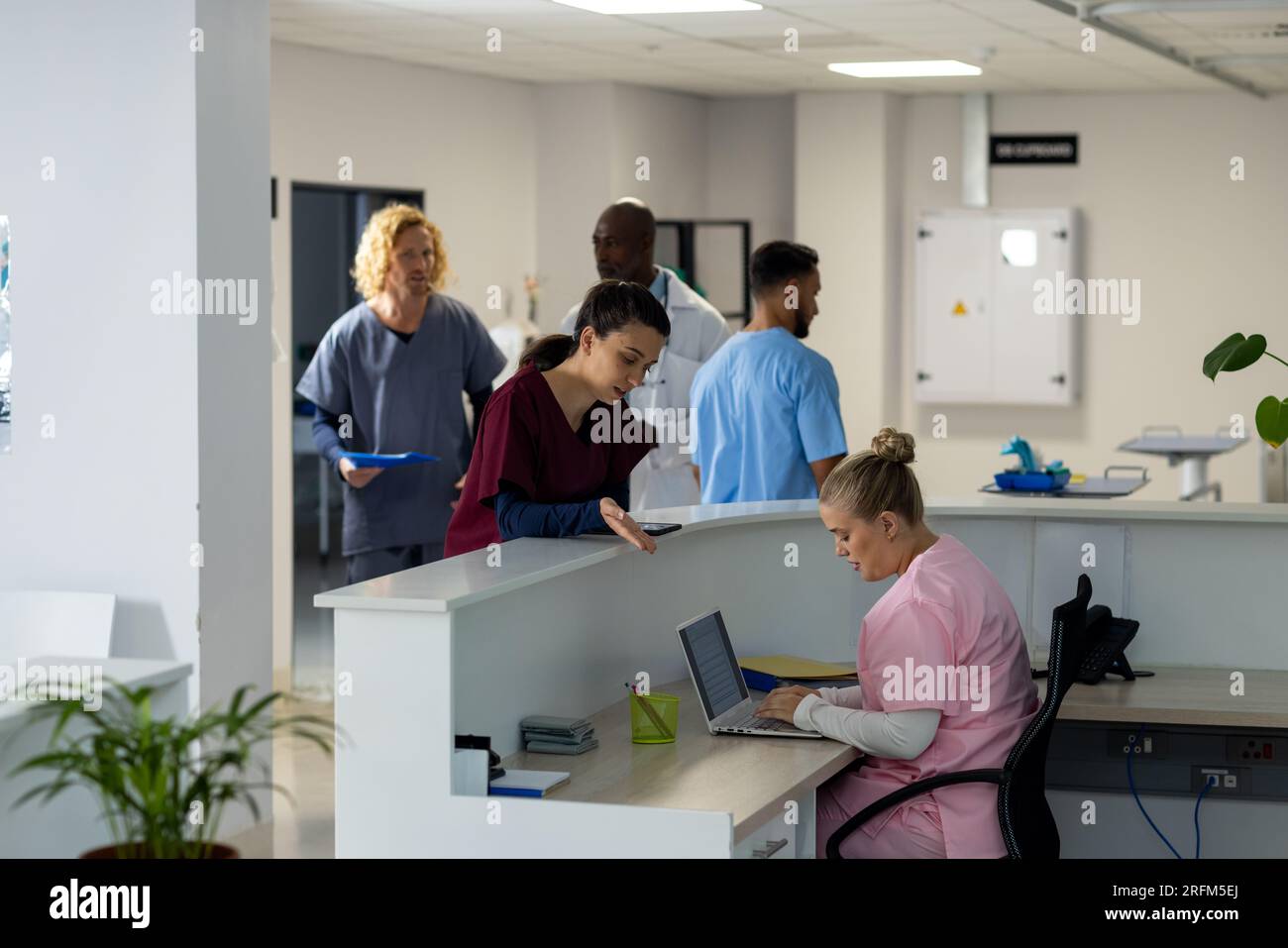 Verschiedene Ärzte, die sich an der Rezeption des Krankenhauses unterhalten Stockfoto