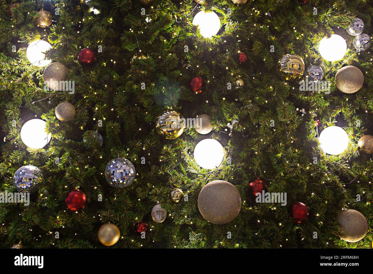 Nahaufnahme der Bälle am Weihnachtsbaum. Bokeh-Girlanden im Hintergrund. Neujahrskonzept. Stockfoto