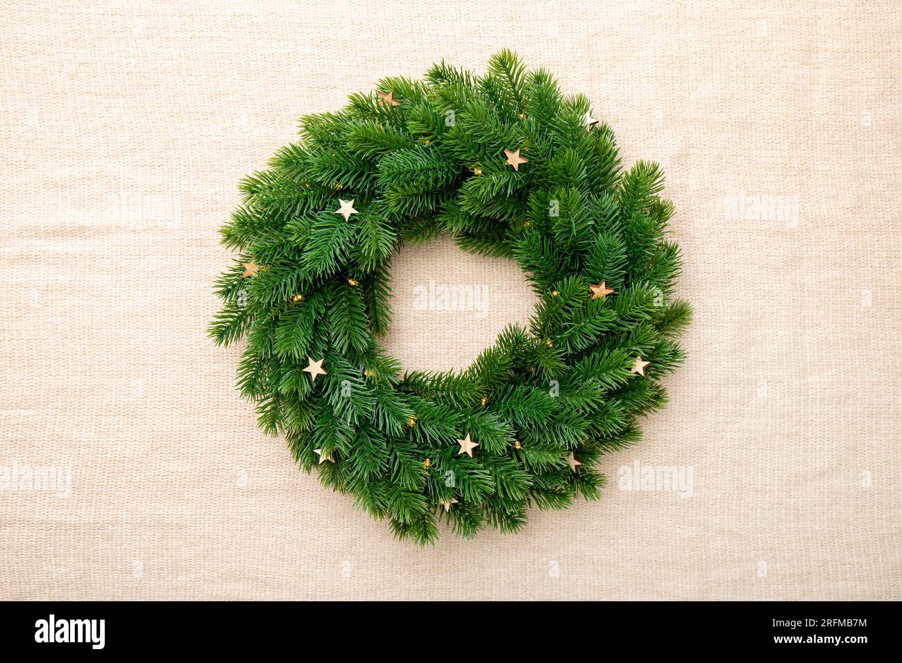 Leerer grüner minimaler Weihnachtskranz auf braunem Textiltuch. Stockfoto