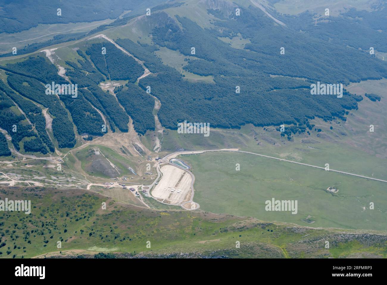 Luftlandschaft, von einem Segelflugzeug, mit Bergresort auf unfruchtbarem Hochland, von Südosten in hellem Sommerlicht auf Campo Felice, Apennines, Stockfoto