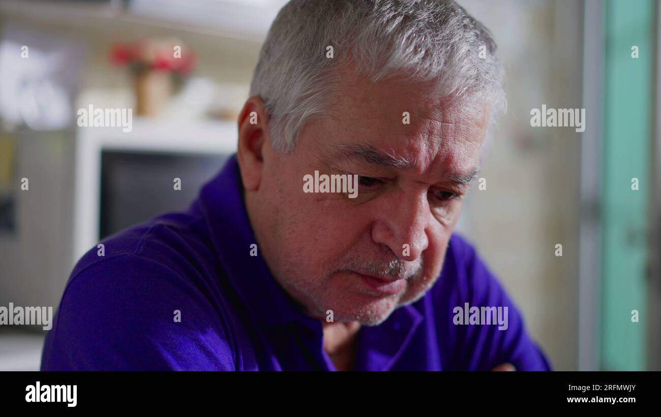 Ein hoffnungsloser Senior-Mann, der allein zu Hause mit Depressionen zu kämpfen hat. Nahgesicht eines älteren Menschen in stiller Verzweiflung, melancholischer und psychischer Erkrankung dargestellt Stockfoto
