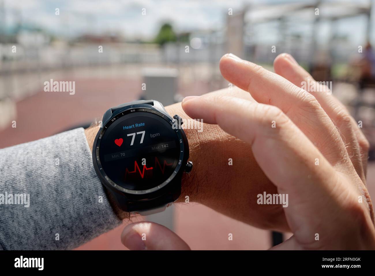 Nahaufnahme des Smart Watch Health Tracker mit der auf dem Bildschirm angezeigten Herzfrequenz. Modernes, elegantes und innovatives tragbares Gerät. Sportler überprüft sein Hörvermögen Stockfoto