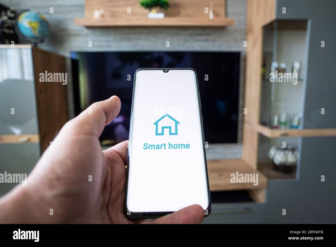 Smart Home-App auf Smartphone. Fernsteuerung elektronischer Geräte in Wohnungen. Konzept der Steuerung von Smart TV, Elektronik im Haus. Internet o Stockfoto