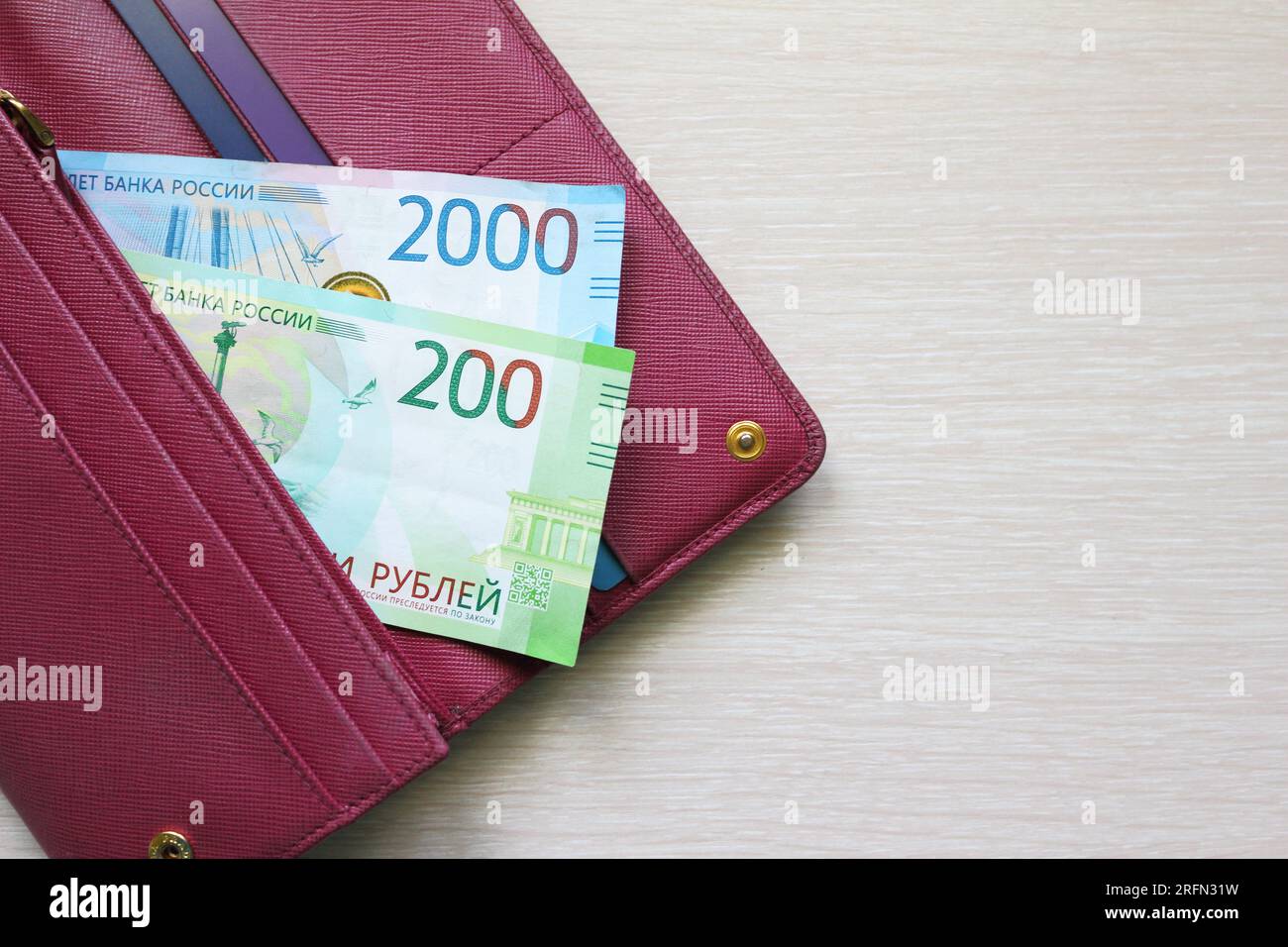 Russische Rubel-Scheine in einer Lederbörse. Rote Geldbörse, Handtasche. Holzhintergrund. Banknoten. Geld in bar. Ein Fan von Rechnungen. REIBEN Stockfoto